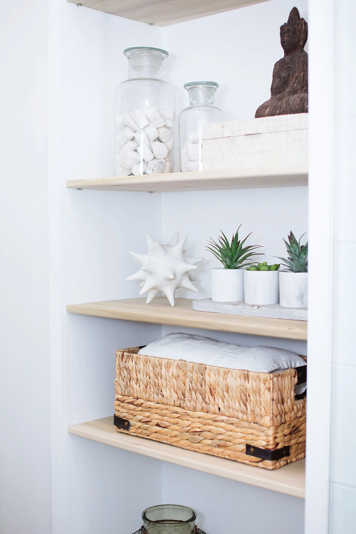 Coastal bath accessories on floor to ceiling shelves in guest bathroom