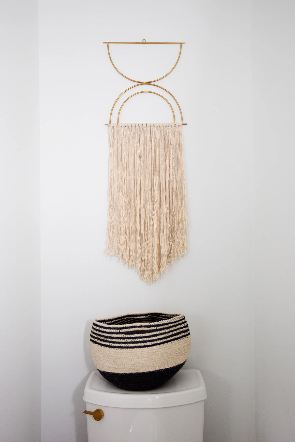Boho fringe art above toilet in master bathroom