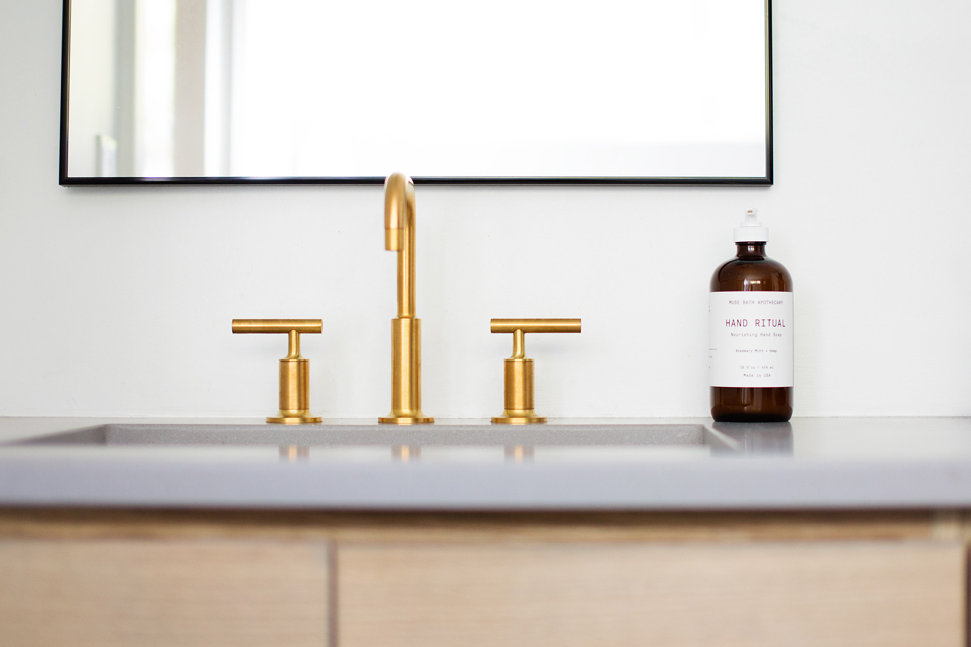 Sleek brushed brass faucet in midcentury modern master bathroom