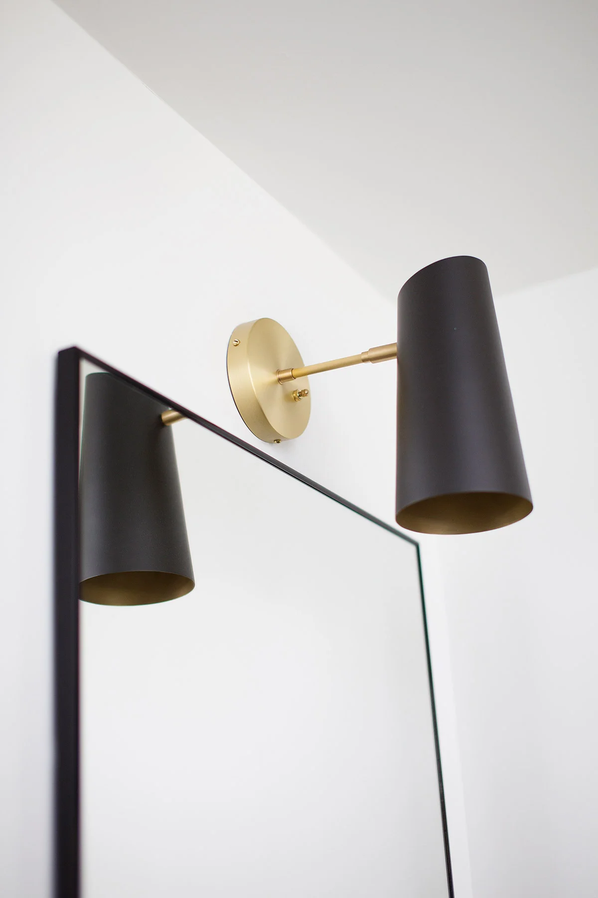 Midcentury modern brass sconce with black shade in master bathroom