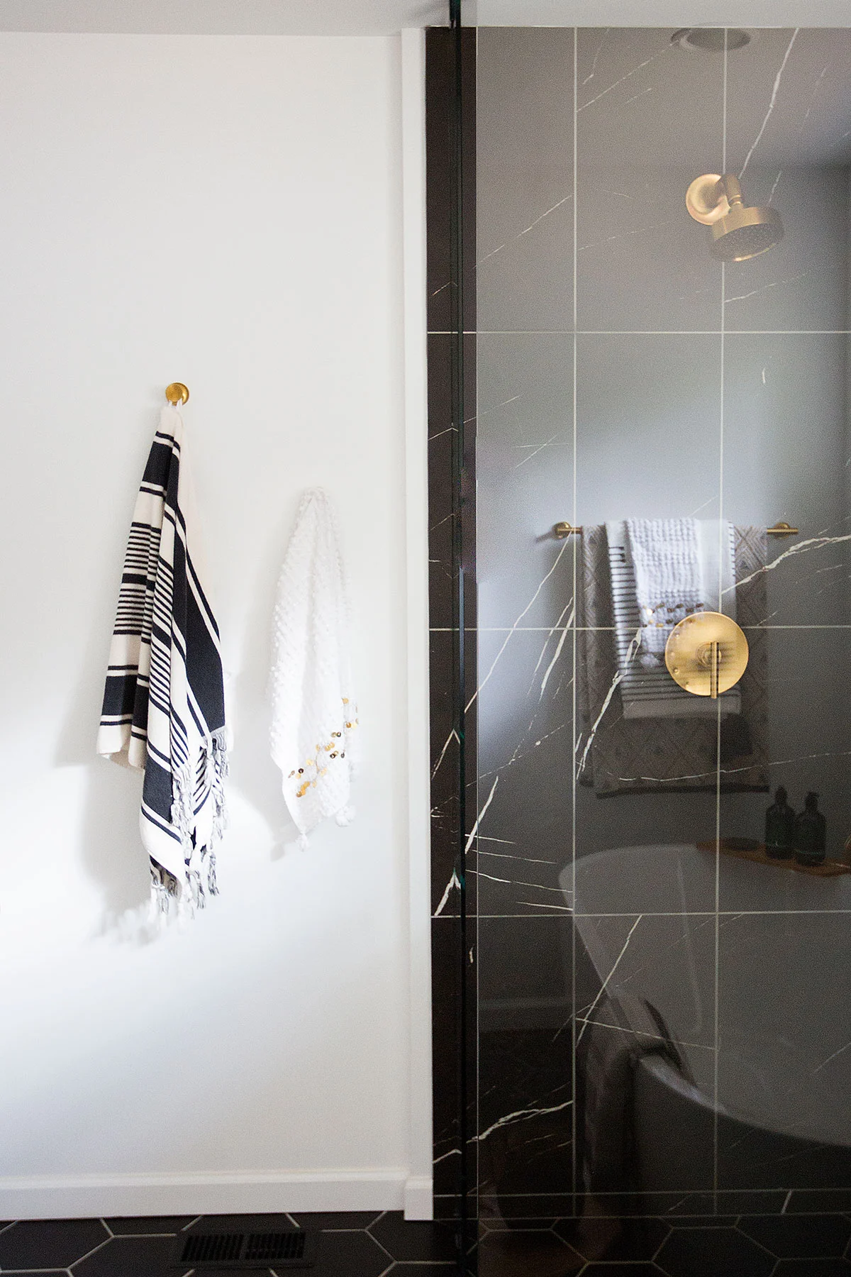 Walk-in shower with black marble tiles and brushed brass hardware in master bathroom