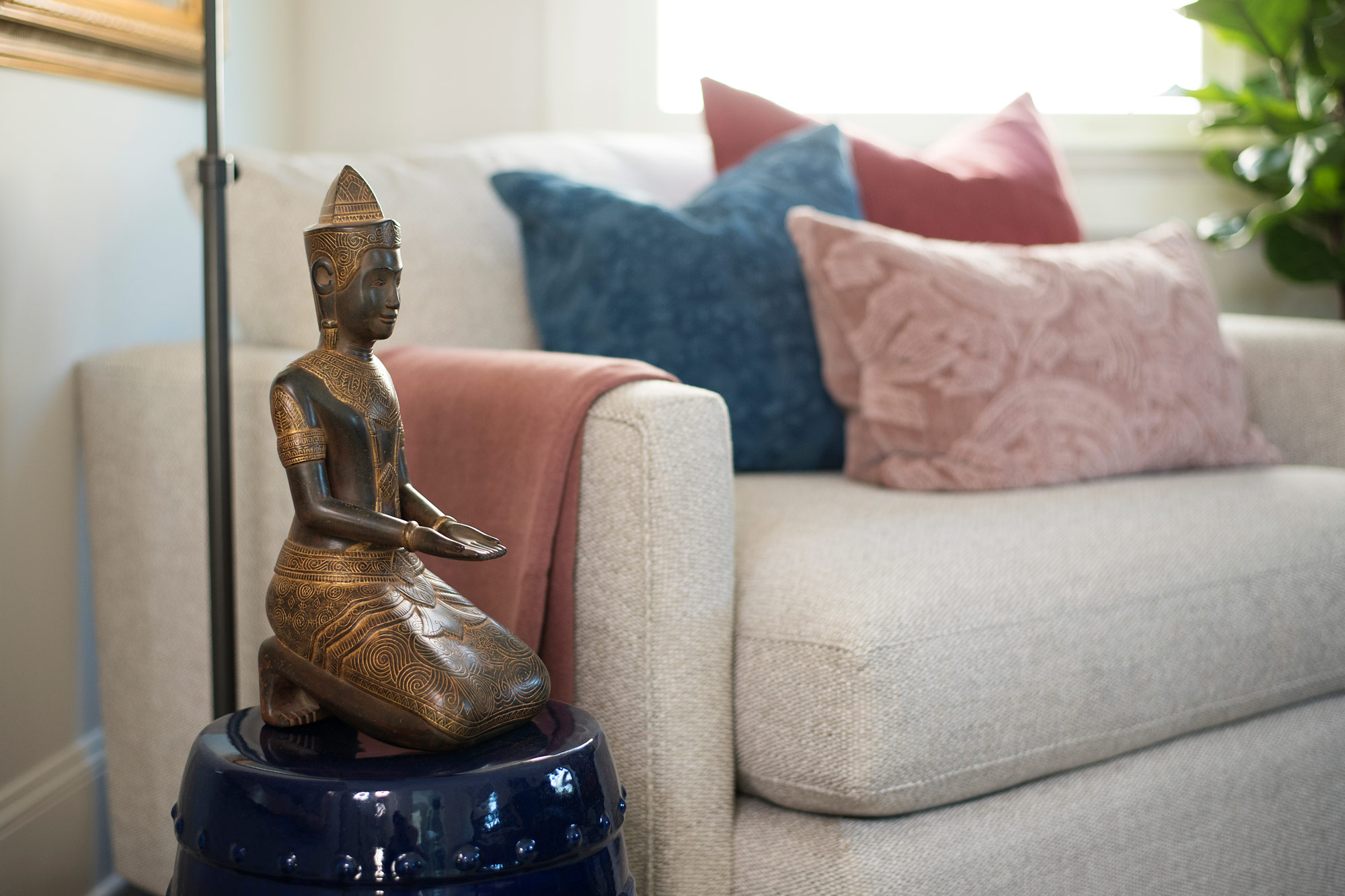 Sitting area in master bedroom with blue and pink pillows and buddha