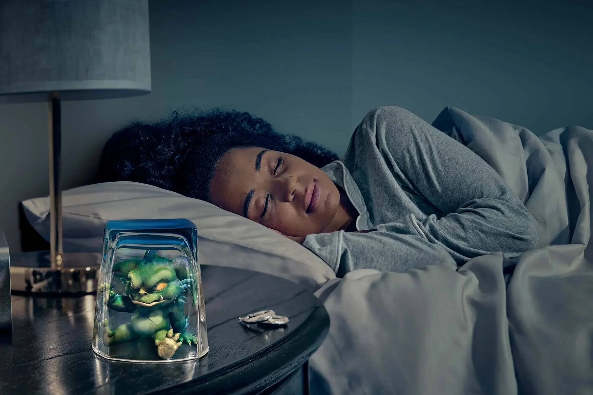 A woman sleeping in bed with a Teenage Mutant Ninja Turtles toy on a nightstand.