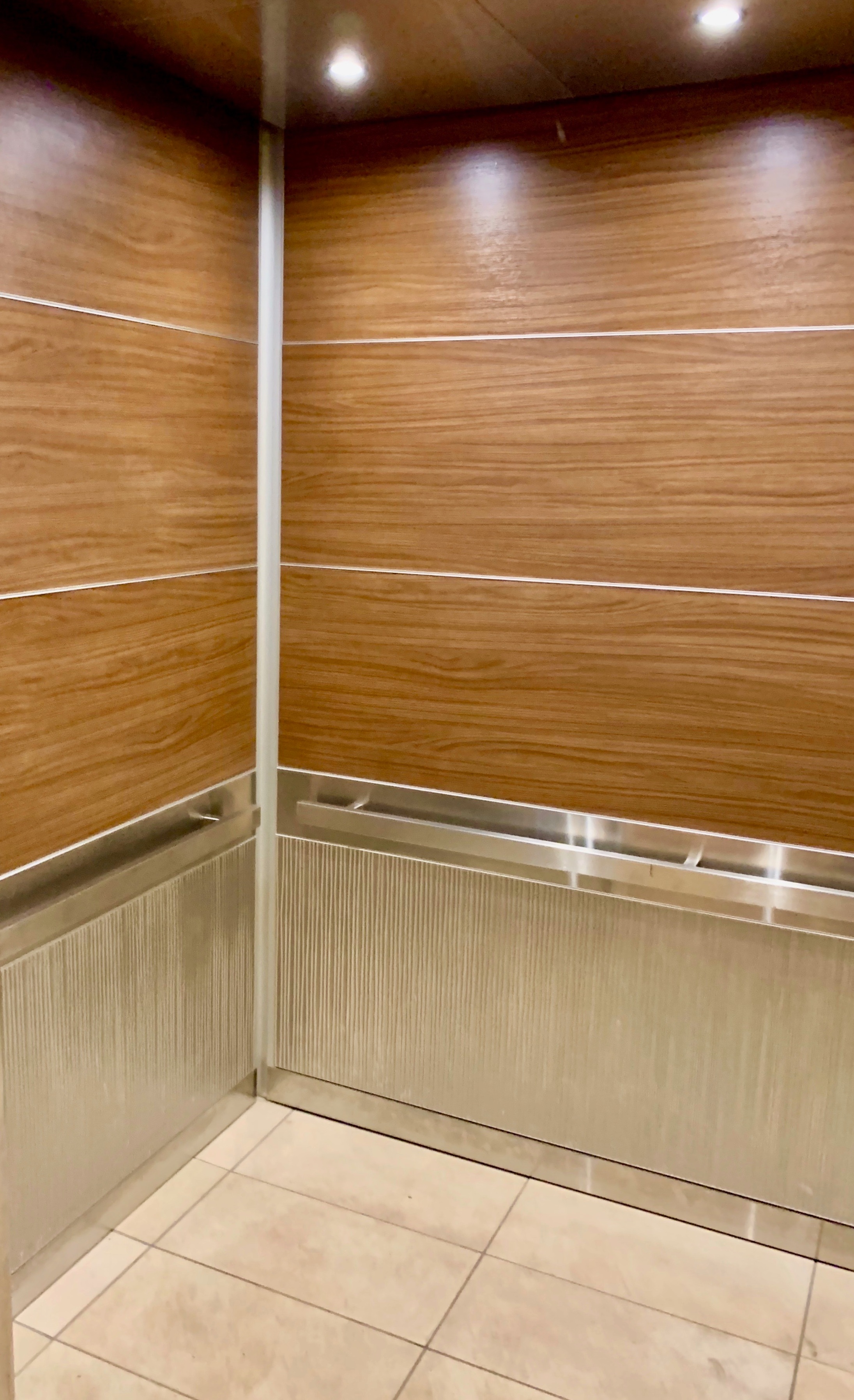 Marriott Suites Midtown - Installed brushed stainless steel ceiling with LED downlights, veneer upper wall panels architectural metal on the bottom wall panels with tile flooring.