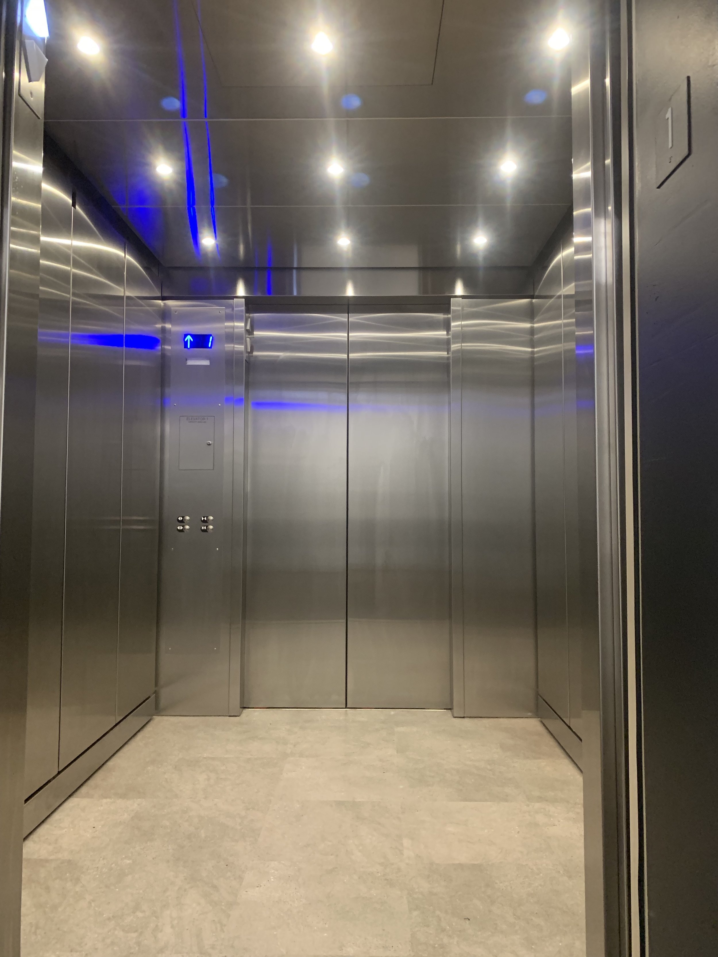 Installed brushed stainless steel ceiling with LED downlights, brushed stainless steel wall panels, brushed stainless steel reveal package and carpet flooring.