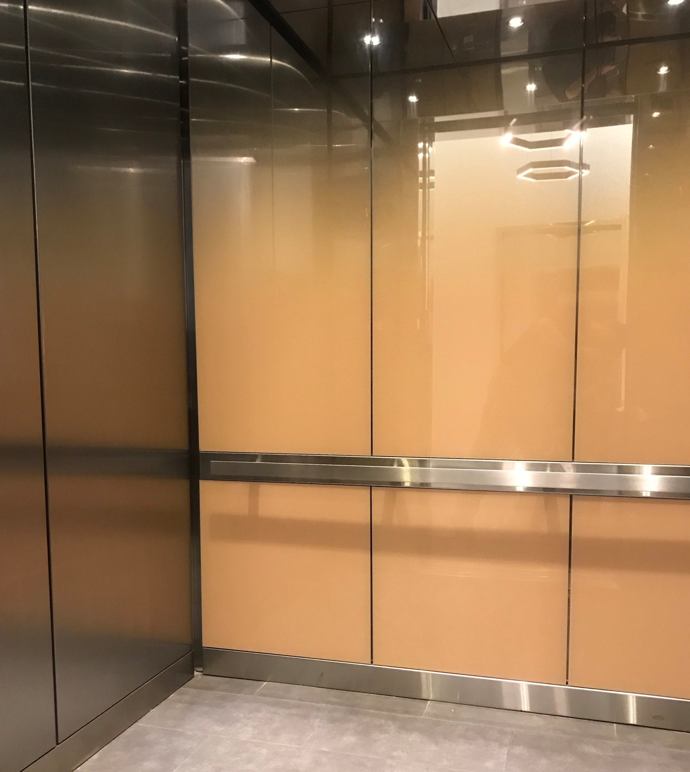 Installed brushed stainless steel ceiling, glass panels on the back wall and brushed stainless steel panels on the side wall and carpet flooring.
