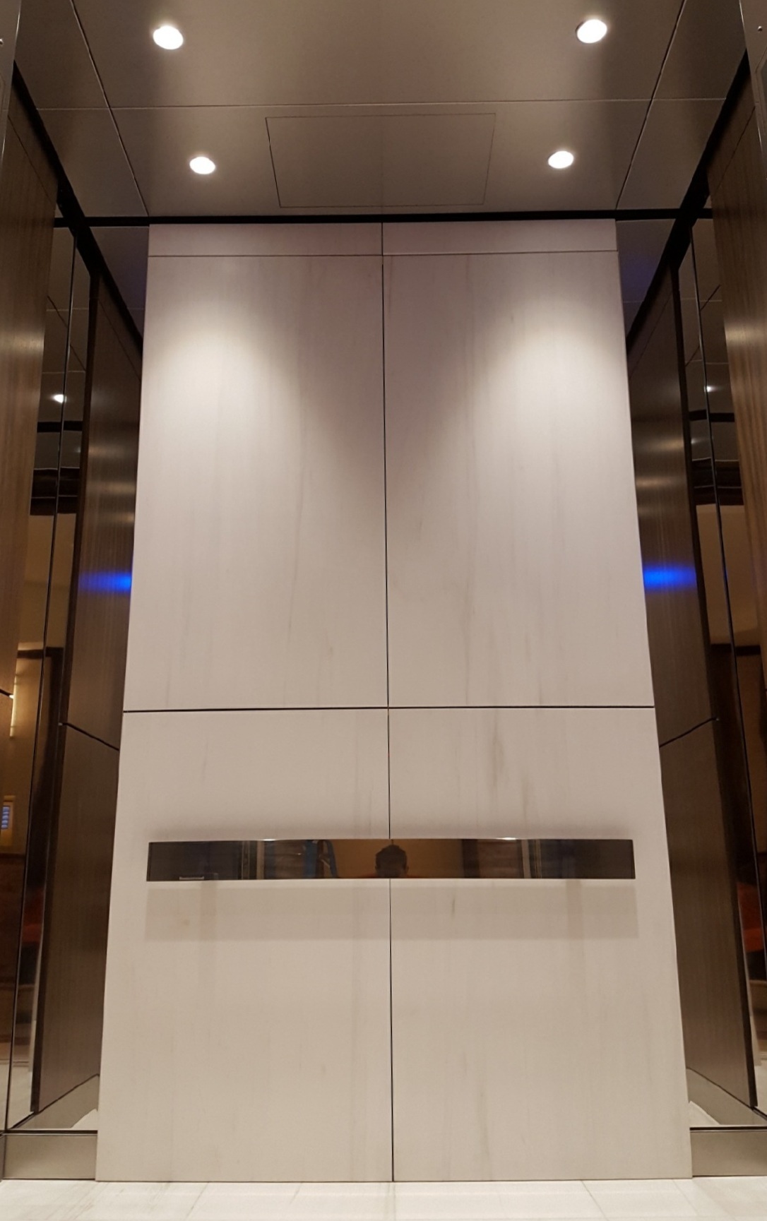 Galleria 100 - Installed brushed stainless steel ceiling marble wall panels on the back wall with stainless steel accent pieces, polished stainless steel handrail with tile flooring.