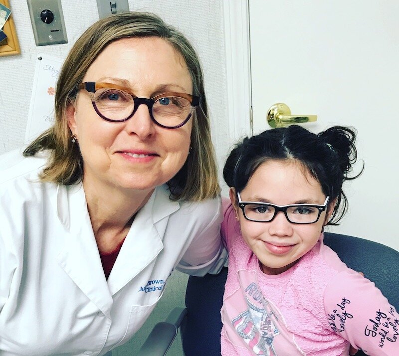 Julie Brown with patient who wears prosthetic ear over microtia