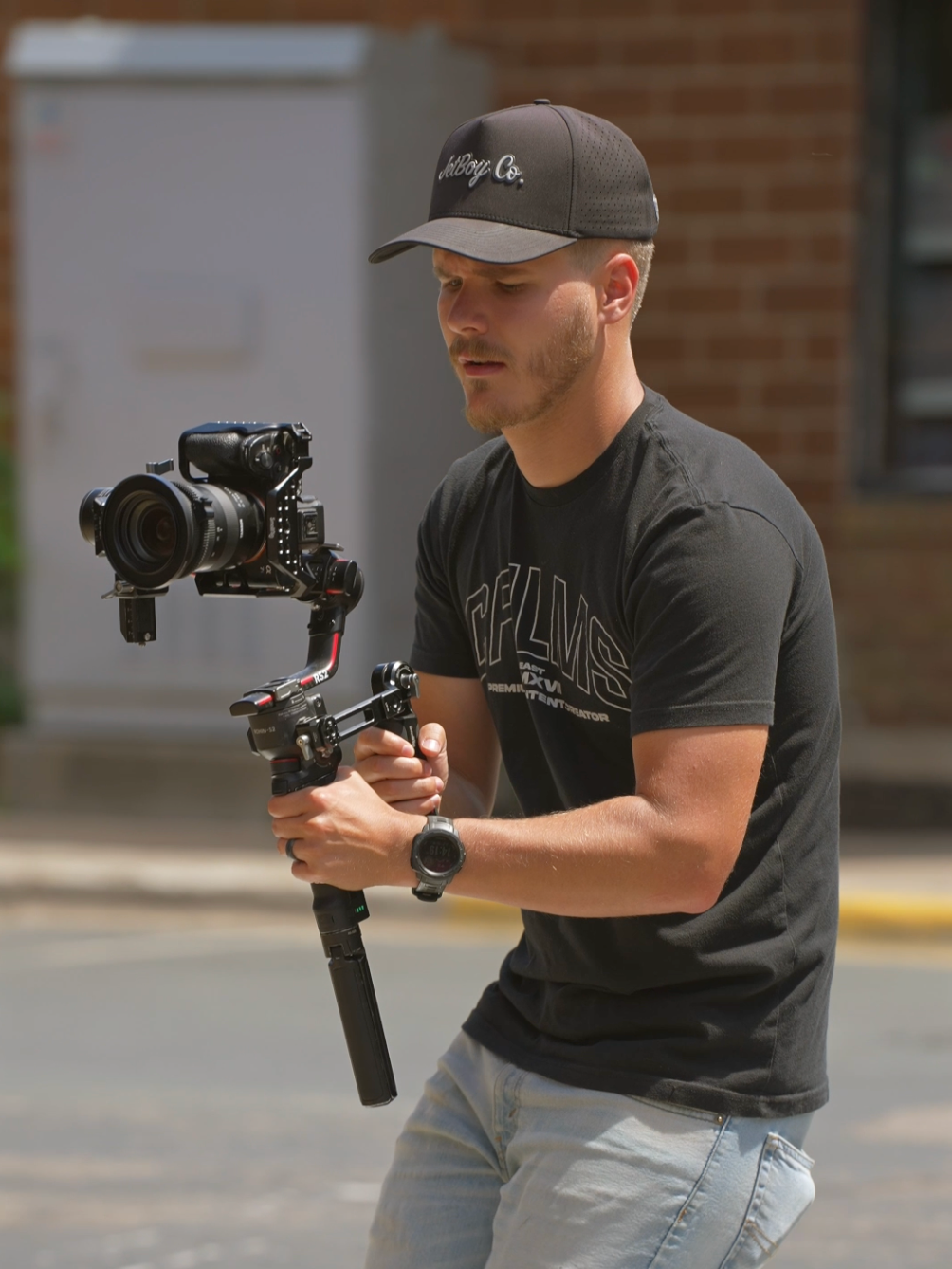 Man operating a camera mounted on a stabilizer outdoors