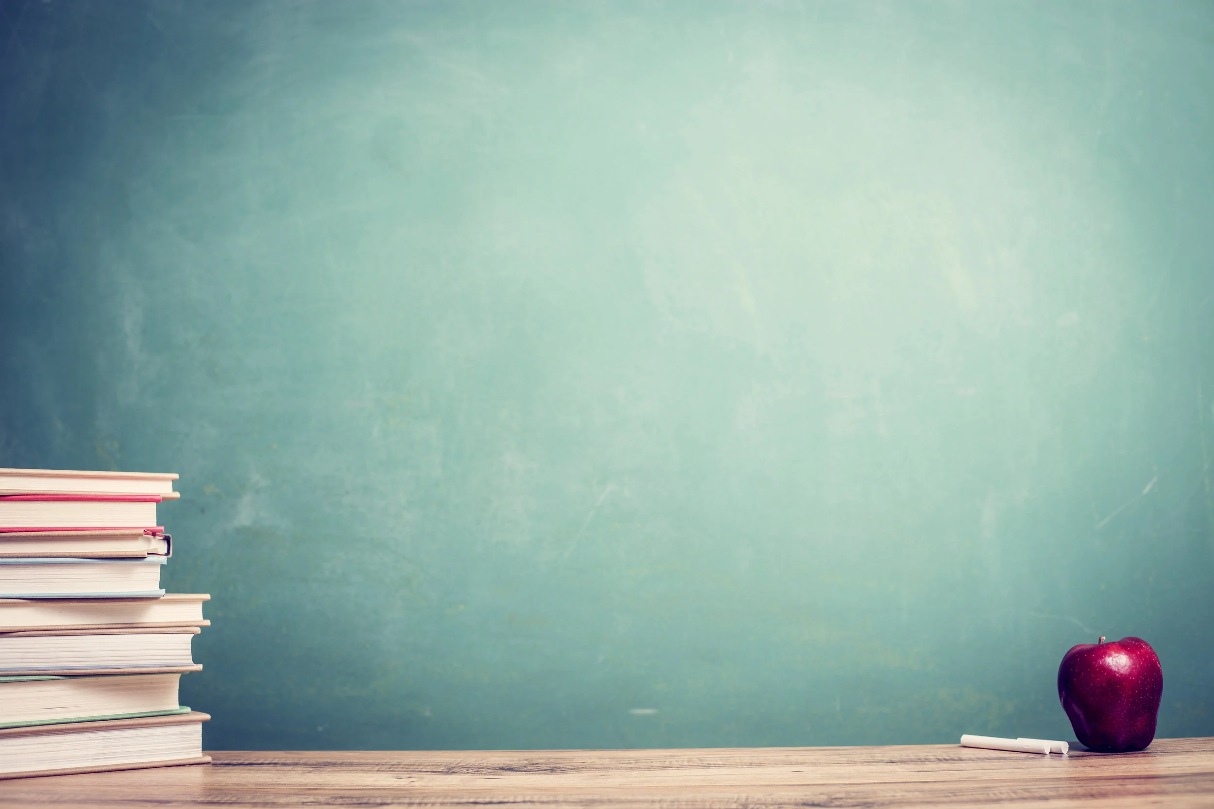 Textbooks,-red-apple-on-wooden-school-desk-with-chalkboard.-1154081807_5760x3840.jpeg