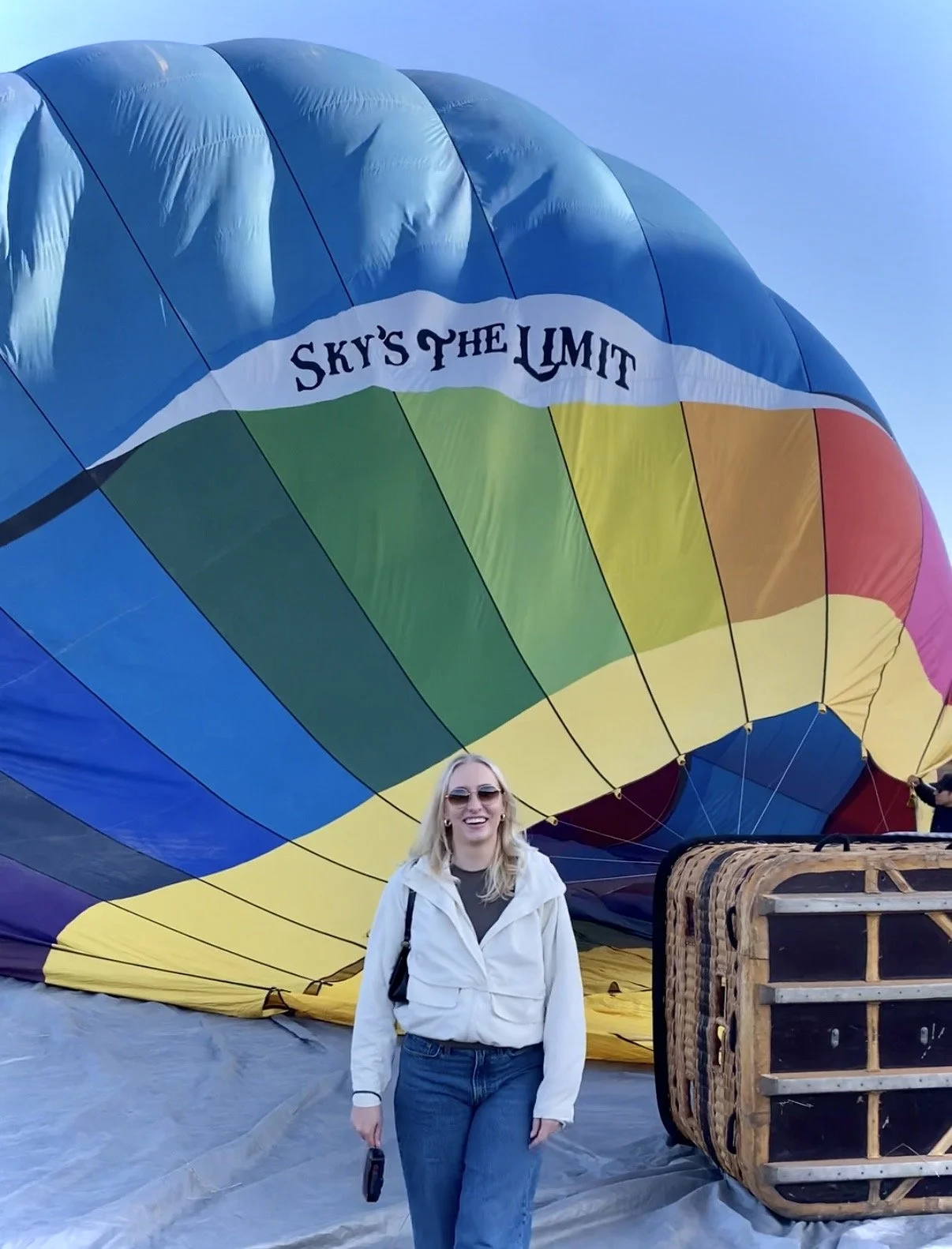 Julie smiling in front of a hot air balloon in Santa Barbara, California with the words sky's the limit.