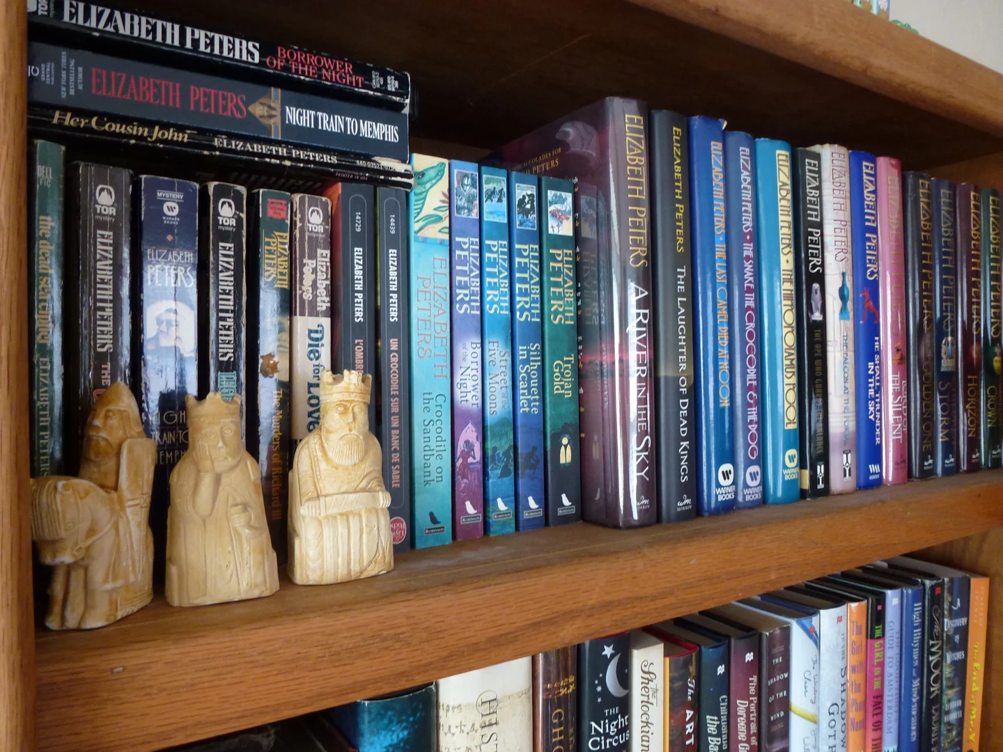 My bookshelf devoted to Elizabeth Peters novels. (And that’s the Lewis Chessmen there on the shelf. These are ones I made out of plaster and painted as a fun project when I was a kid. See, I told you I couldn’t escape my fate.)