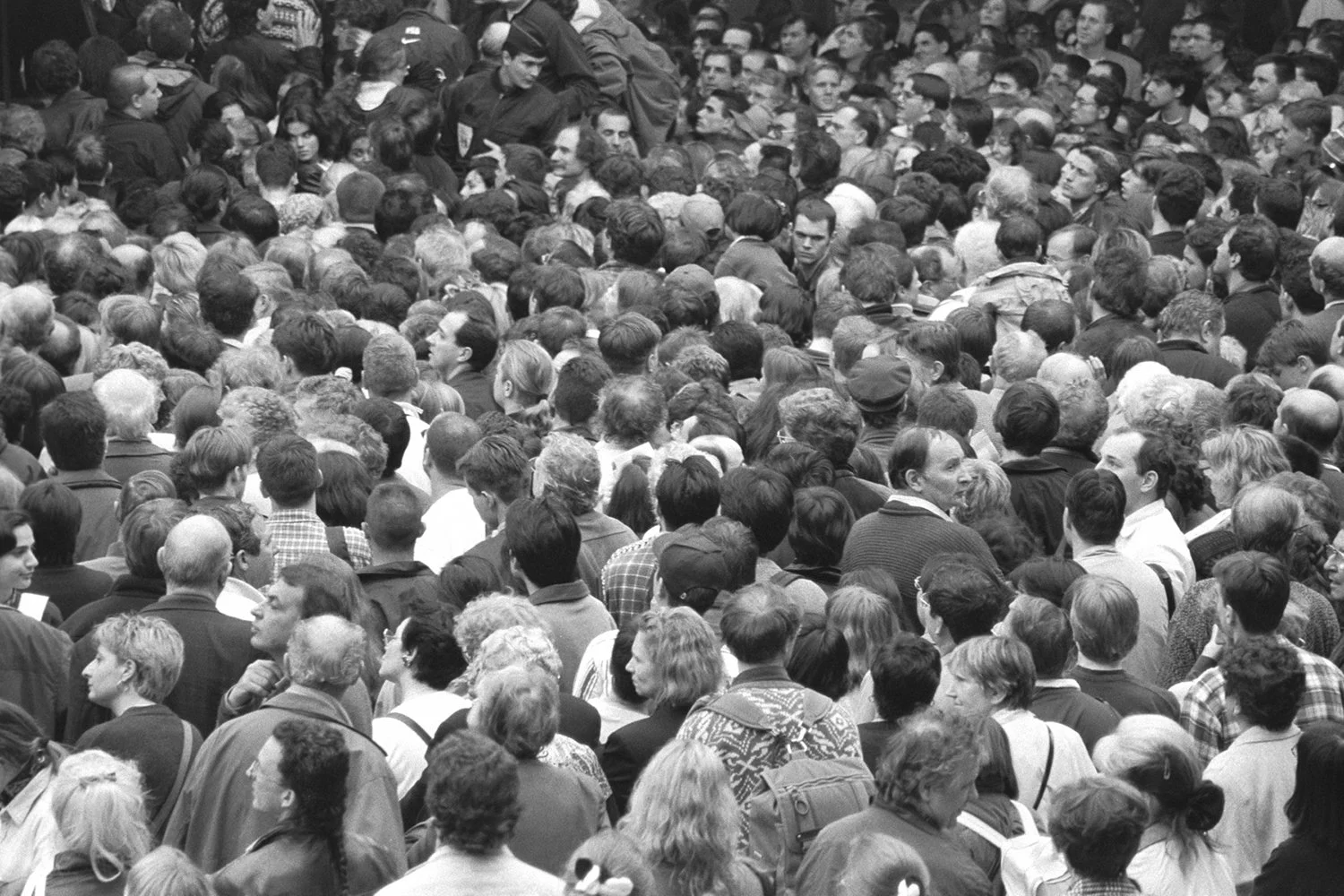 Black and white photograph: A closeup of crowd at the Louvre Museum in Paris during the May 3, 1998 heist of a Corot painting, gathered in the main hall under the pyramid. Photograph by Gigi Pandian.