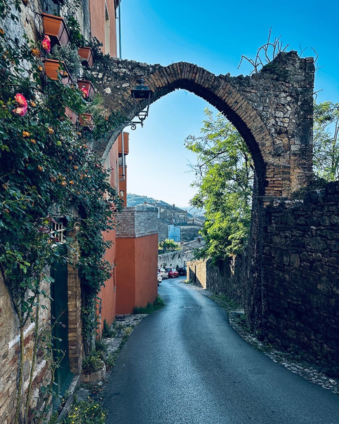 A crumbling old archway over a narrow paved road in Amelia, Italy.