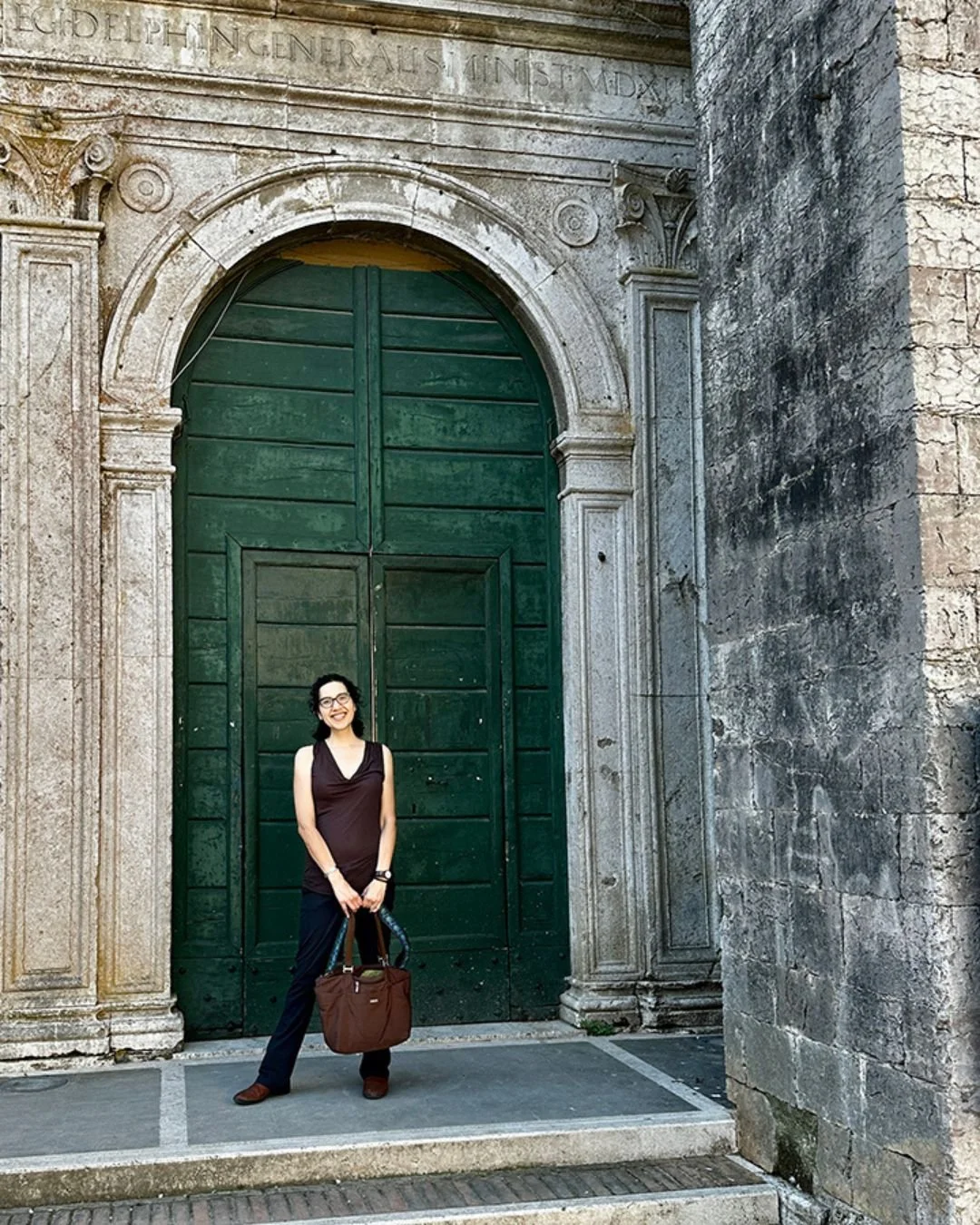Author Gigi Pandian outside the tall green doors of the Collegio Boccarini cloisters in Amelia, Italy.