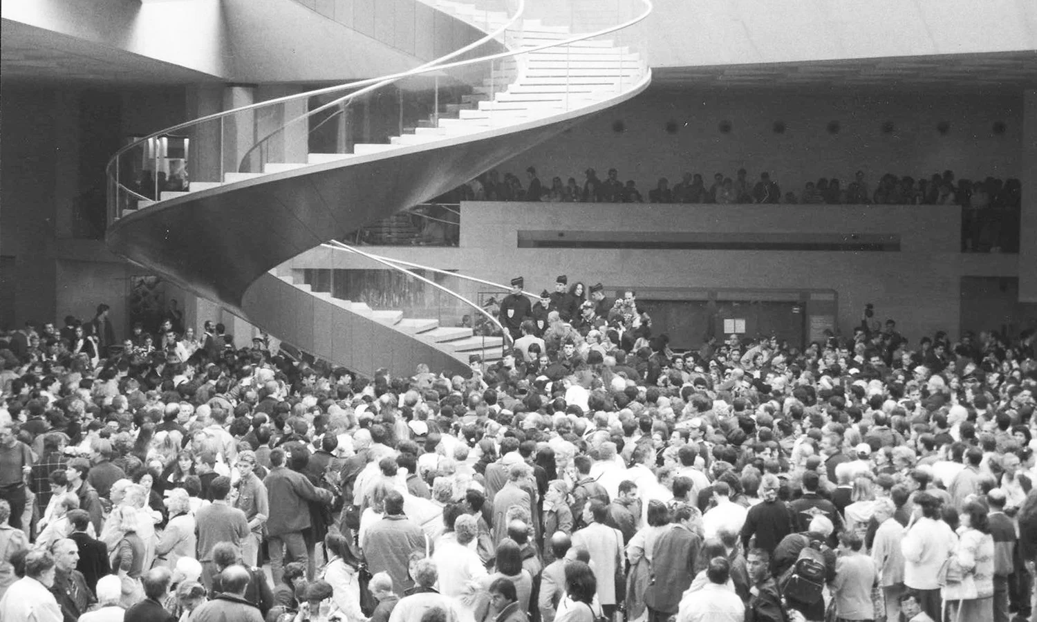 Black and white photograph: A closeup of crowd at the Louvre Museum in Paris during the May 3, 1998 heist of a Corot painting, gathered in the main hall under the pyramid. Photograph by Gigi Pandian.