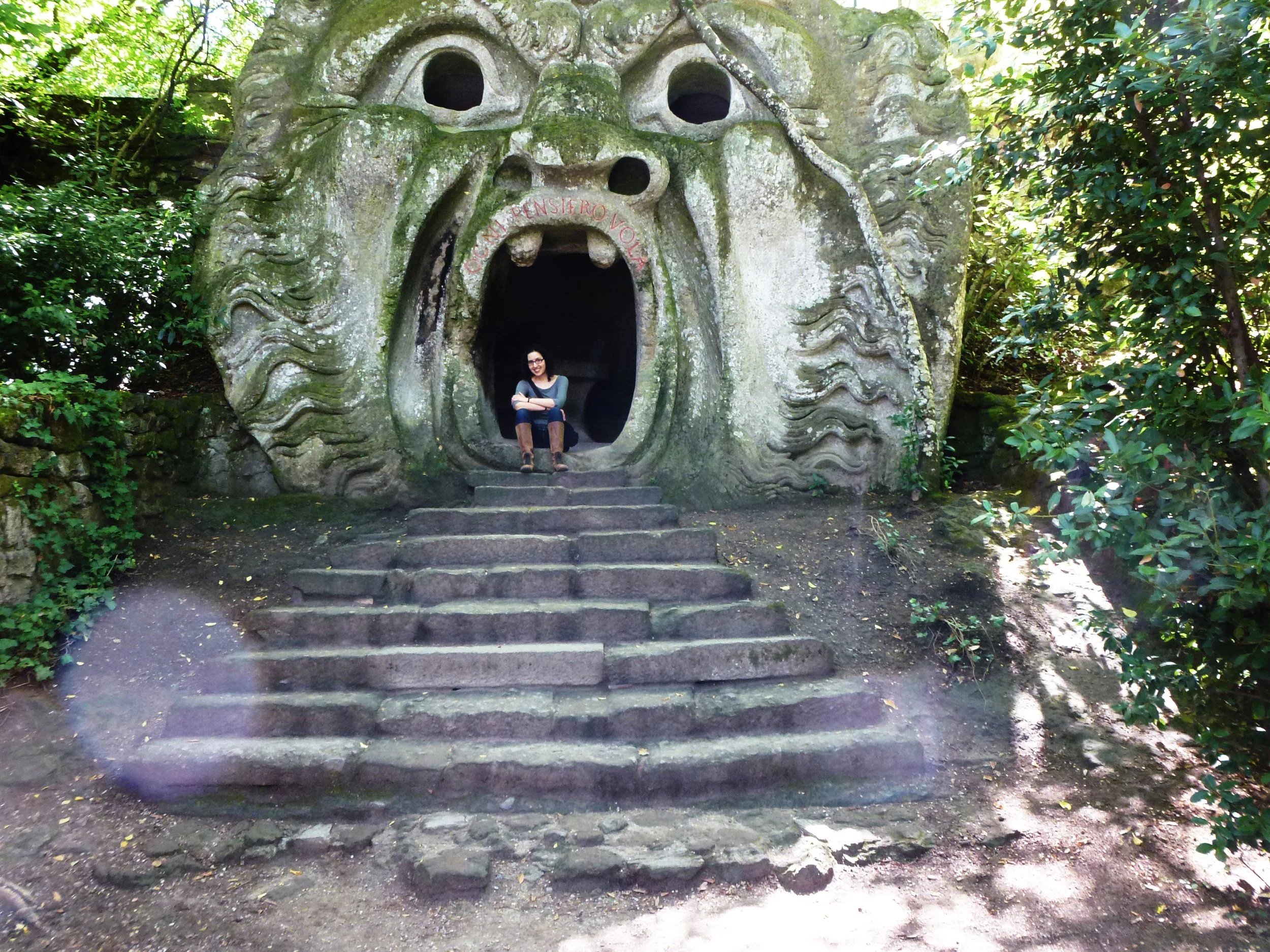 Gigi Pandian sitting in the Hell Mouth stone sculpture at Bomarzo Italy's Park of Monsters.