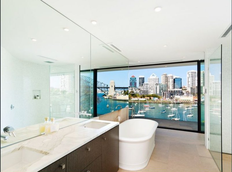  Welcoming bathroom with large tub and views of Sydney. Polished marble counters and floor to ceiling windows. 