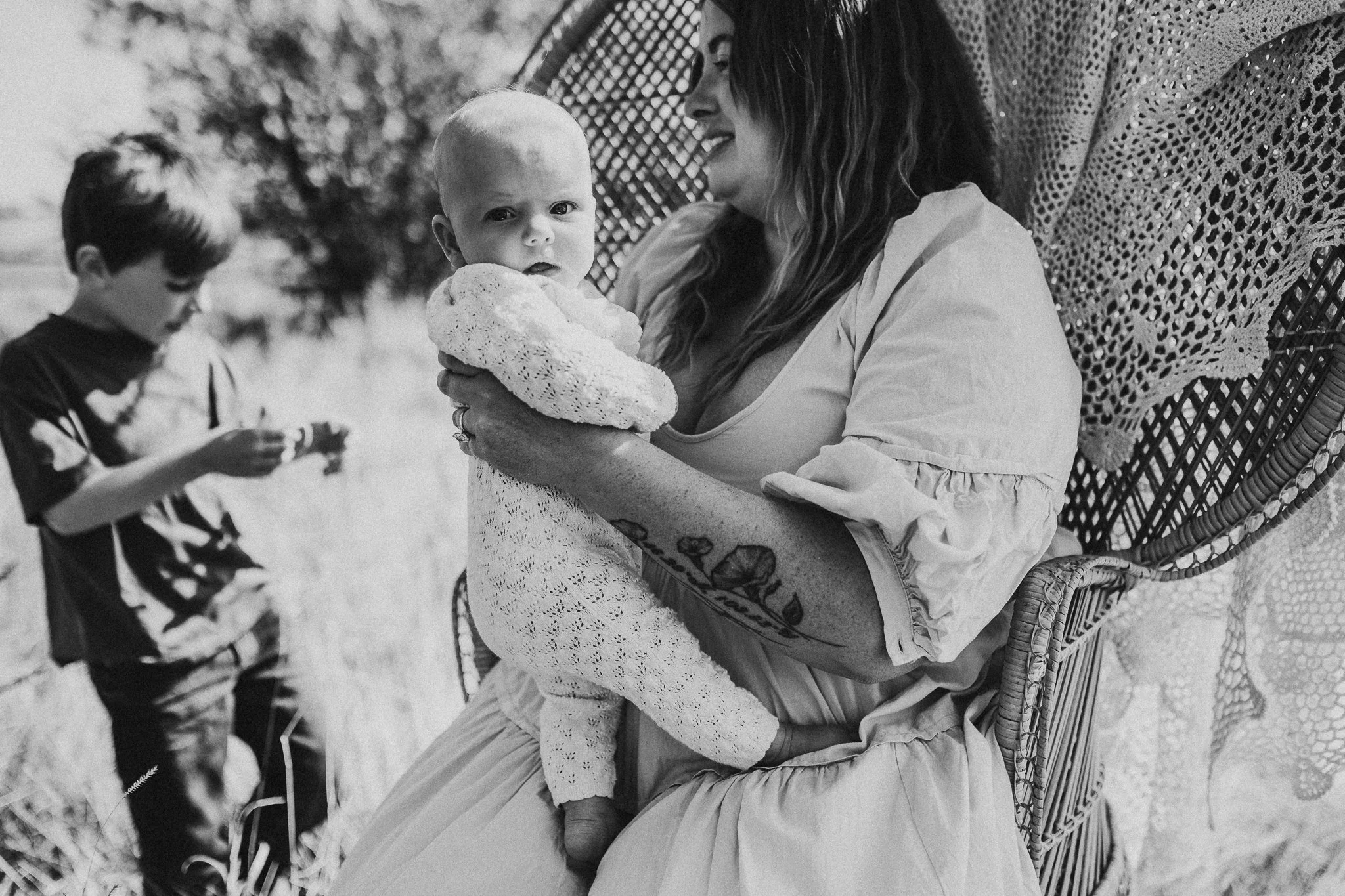 Mother holding baby with older child nearby, black and white family portrait North Dakota