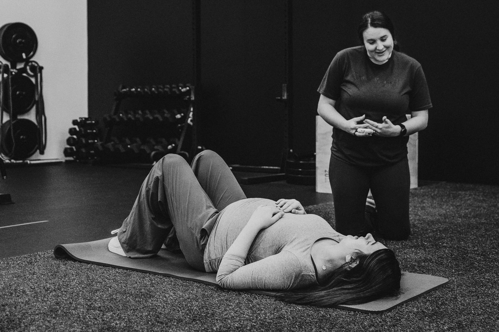 Pregnant woman finding relief from pregnancy sciatica through guided movement and breathing with a prenatal fitness specialist in western North Dakota