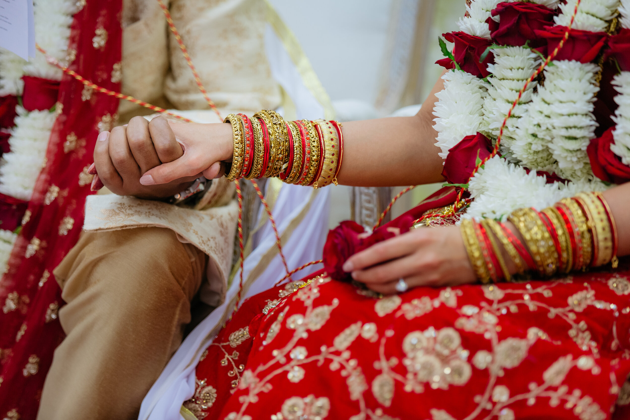 Close up of Bride and Groom holding hands featuring gold jewellery