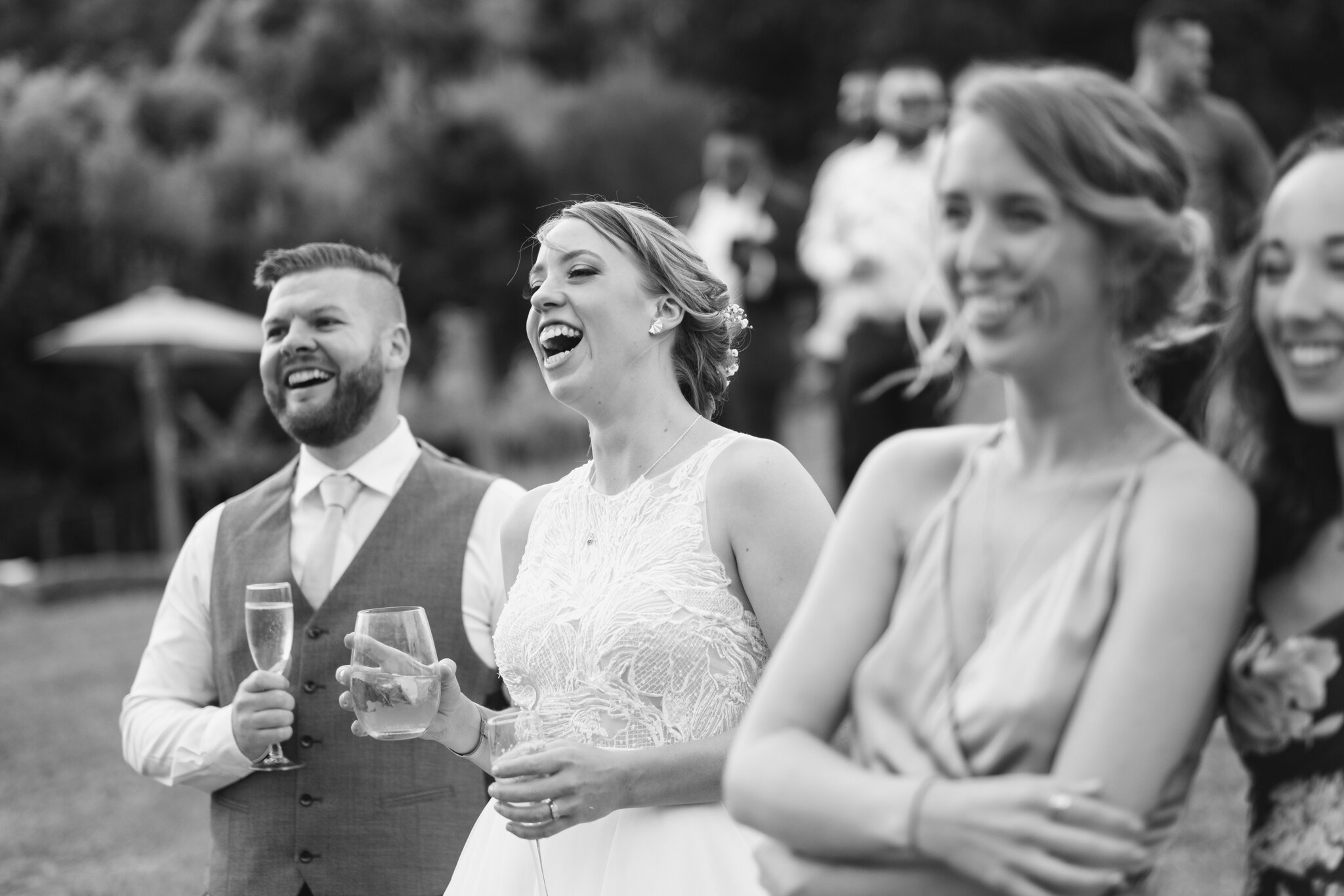 Bride, Groom and guests laughing at wedding speeches