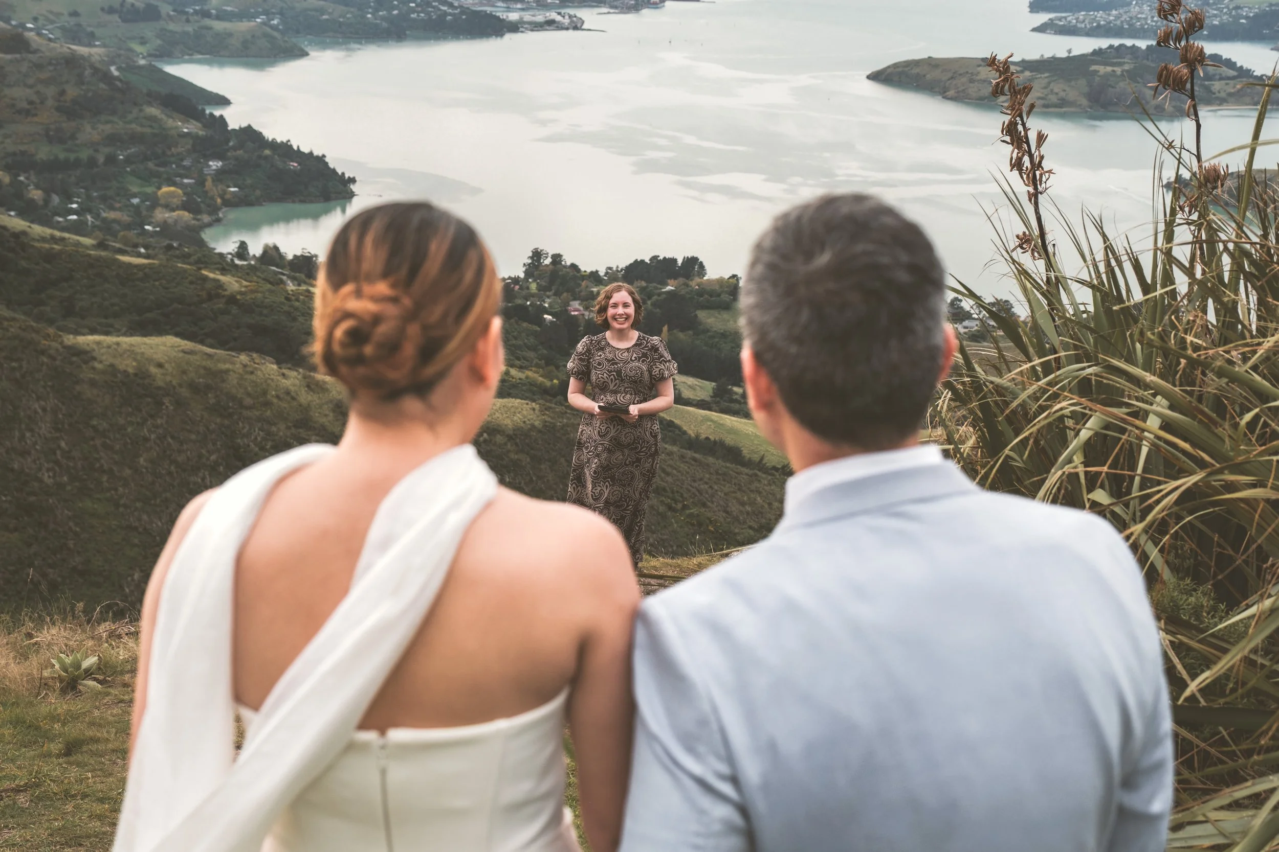 Celebrant between couple overlooking ocean