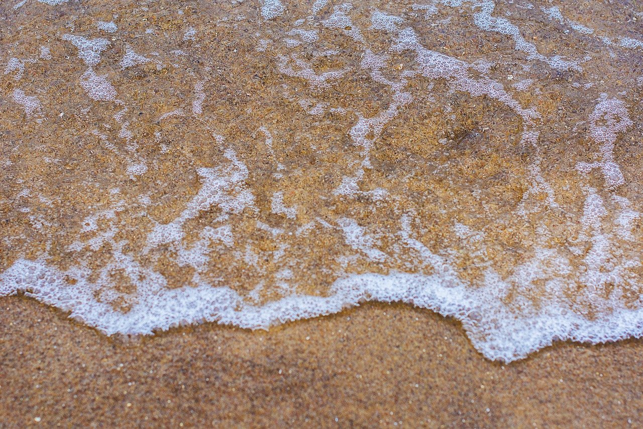small wave foaming at the shoreline of a beach