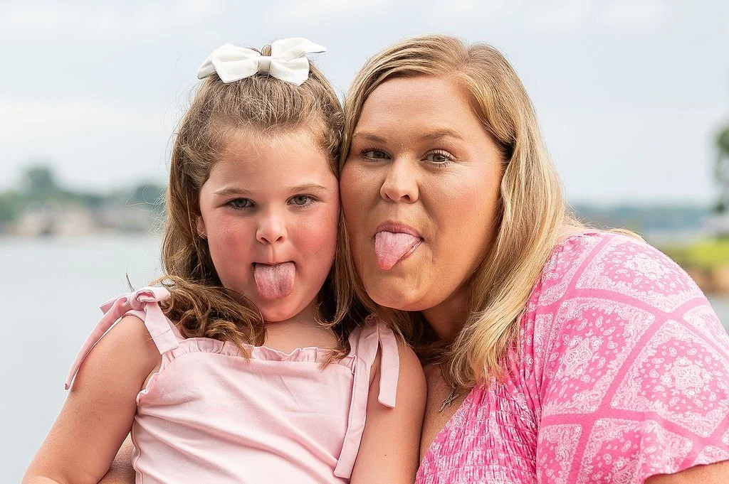 mom and daughter stick out their tongues to the camera for silly photo at outdoor family session lake norman nc