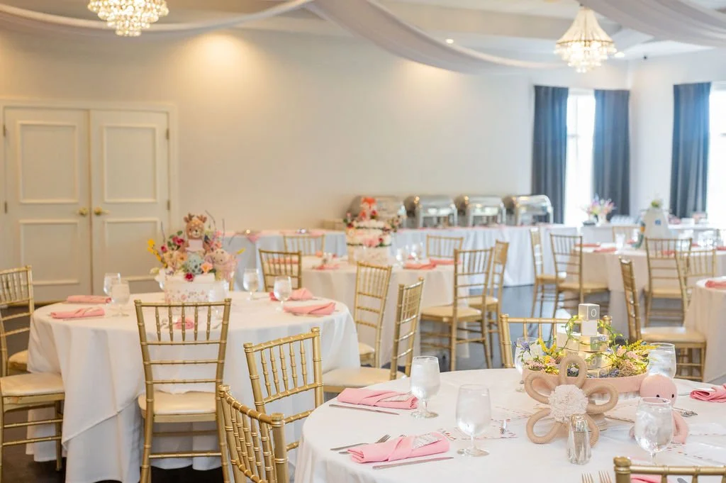 baby shower event space set up photo with white and pink tables capes