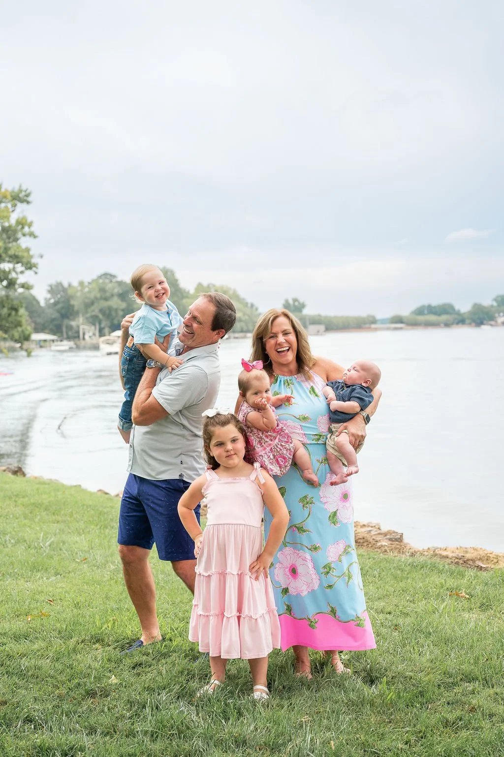grandparents hold and play with their grandkids at outdoor family photo session in lake norman