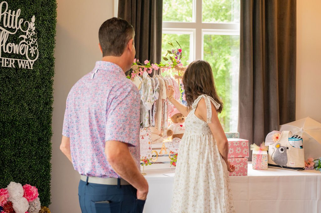 mom and dad browse baby clothes at their baby shower event in huntersville