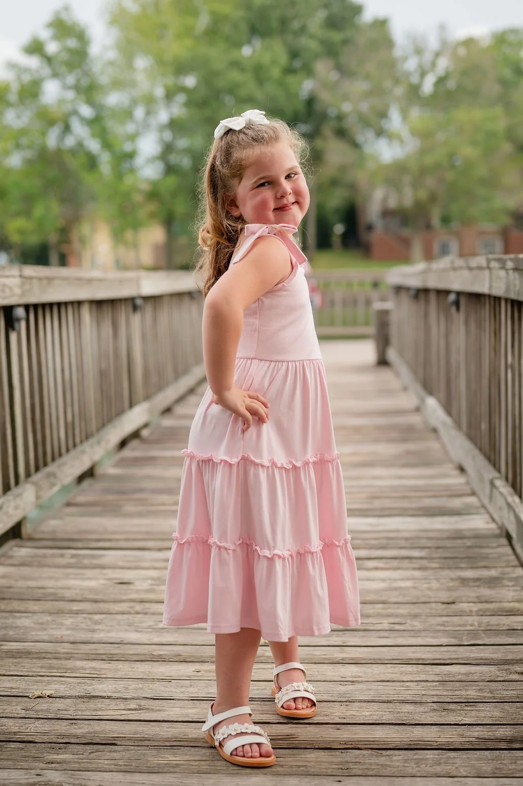 girl poses for camera on wooden bridge during outdoor family session