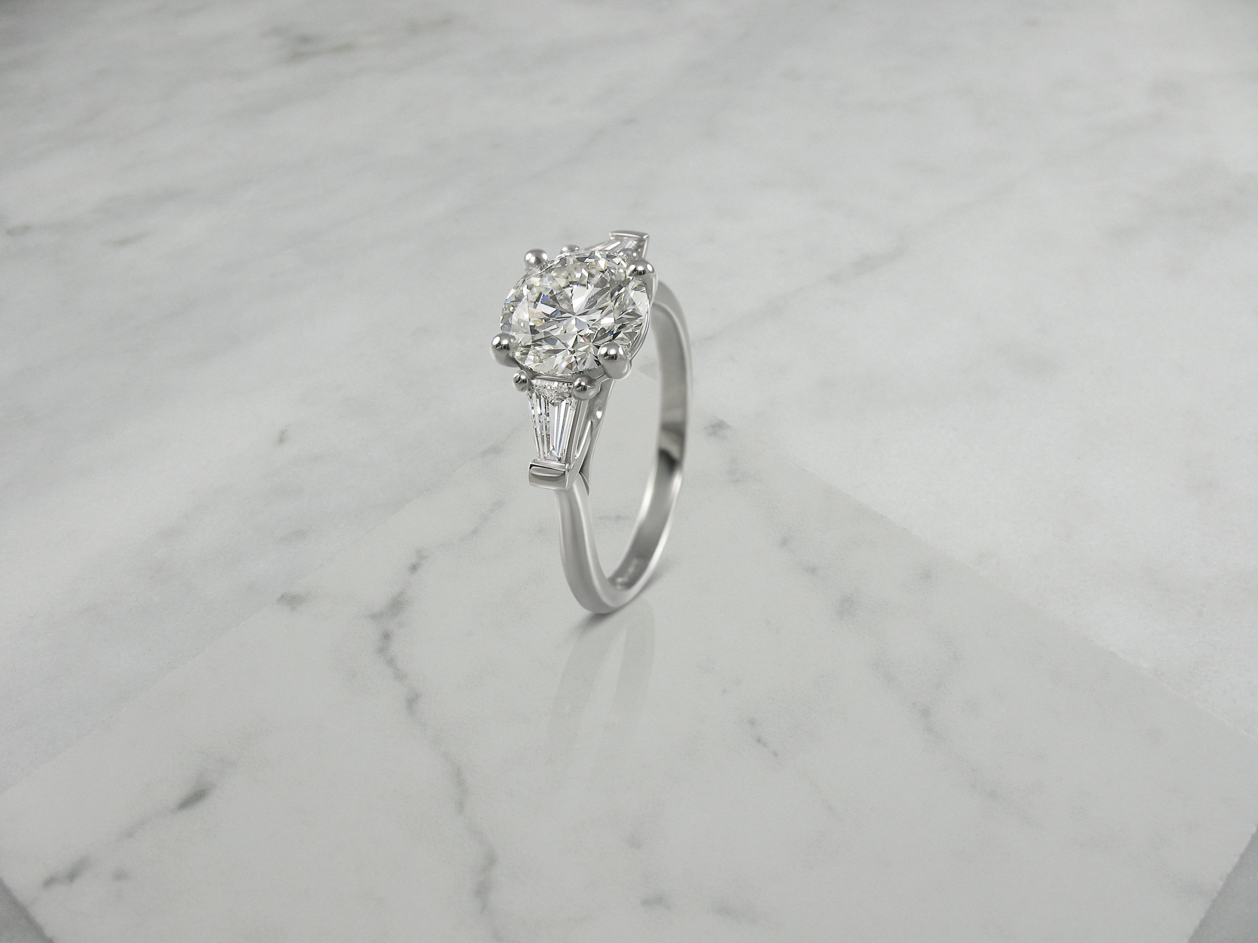 Round brilliant cut diamond and tapered baguette engagement ring