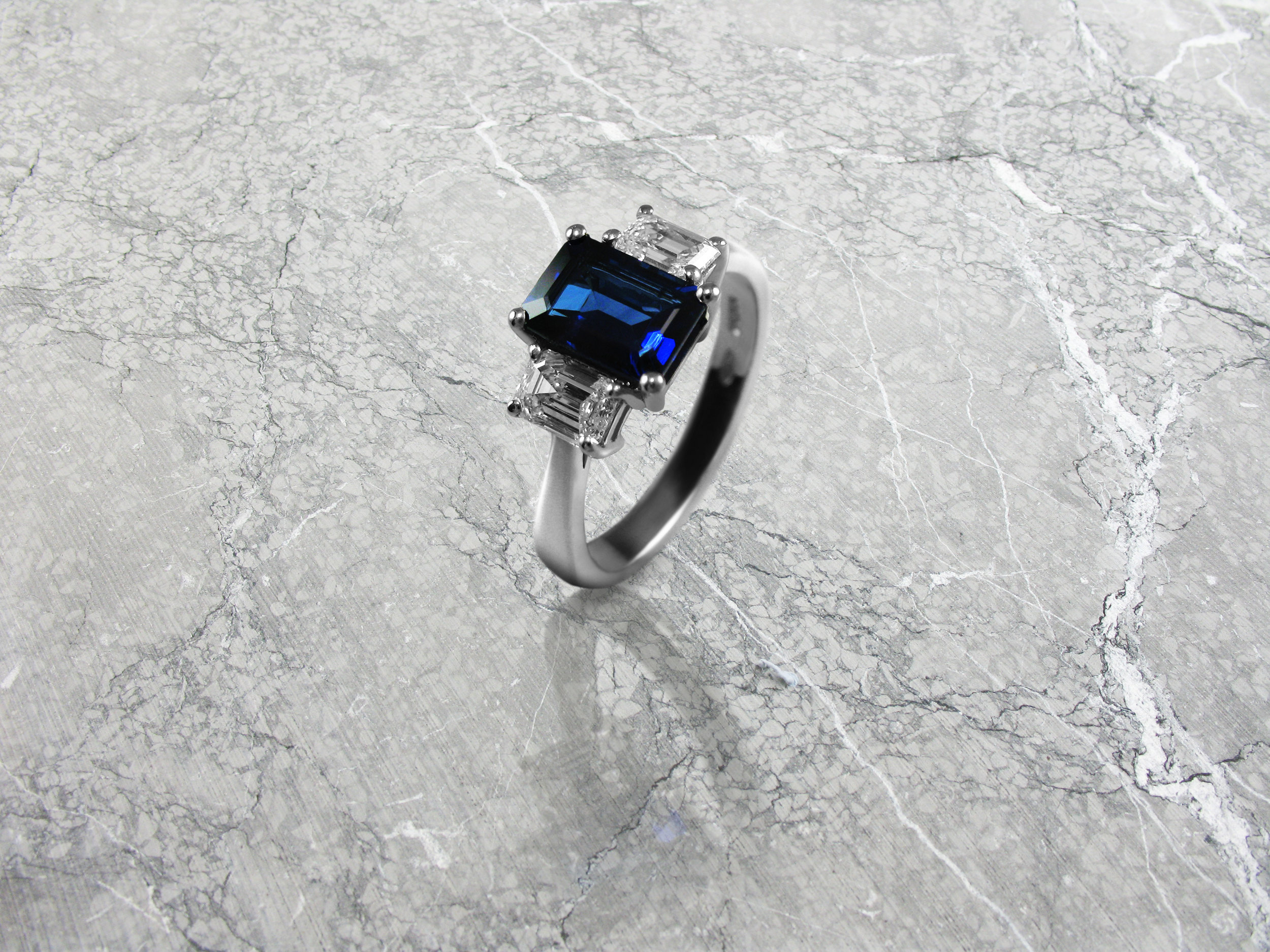 Emerald cut sapphire and diamond trilogy engagement ring