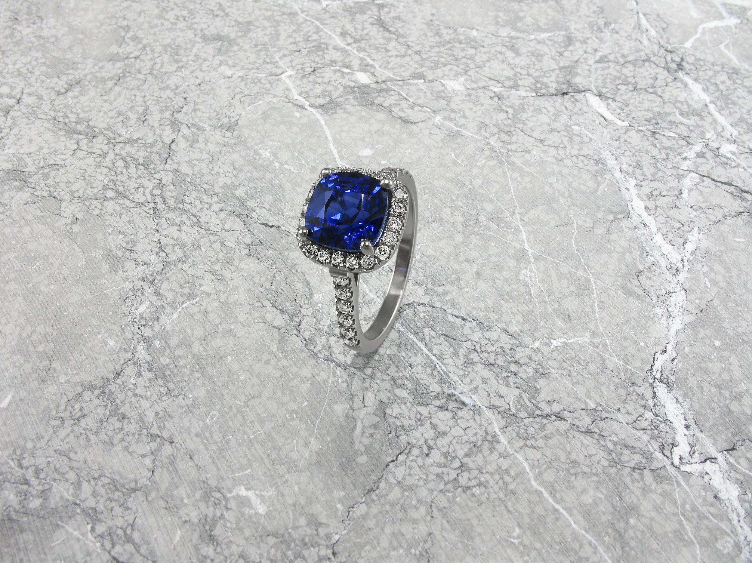 Cushion shaped sapphire and diamond halo engagement ring