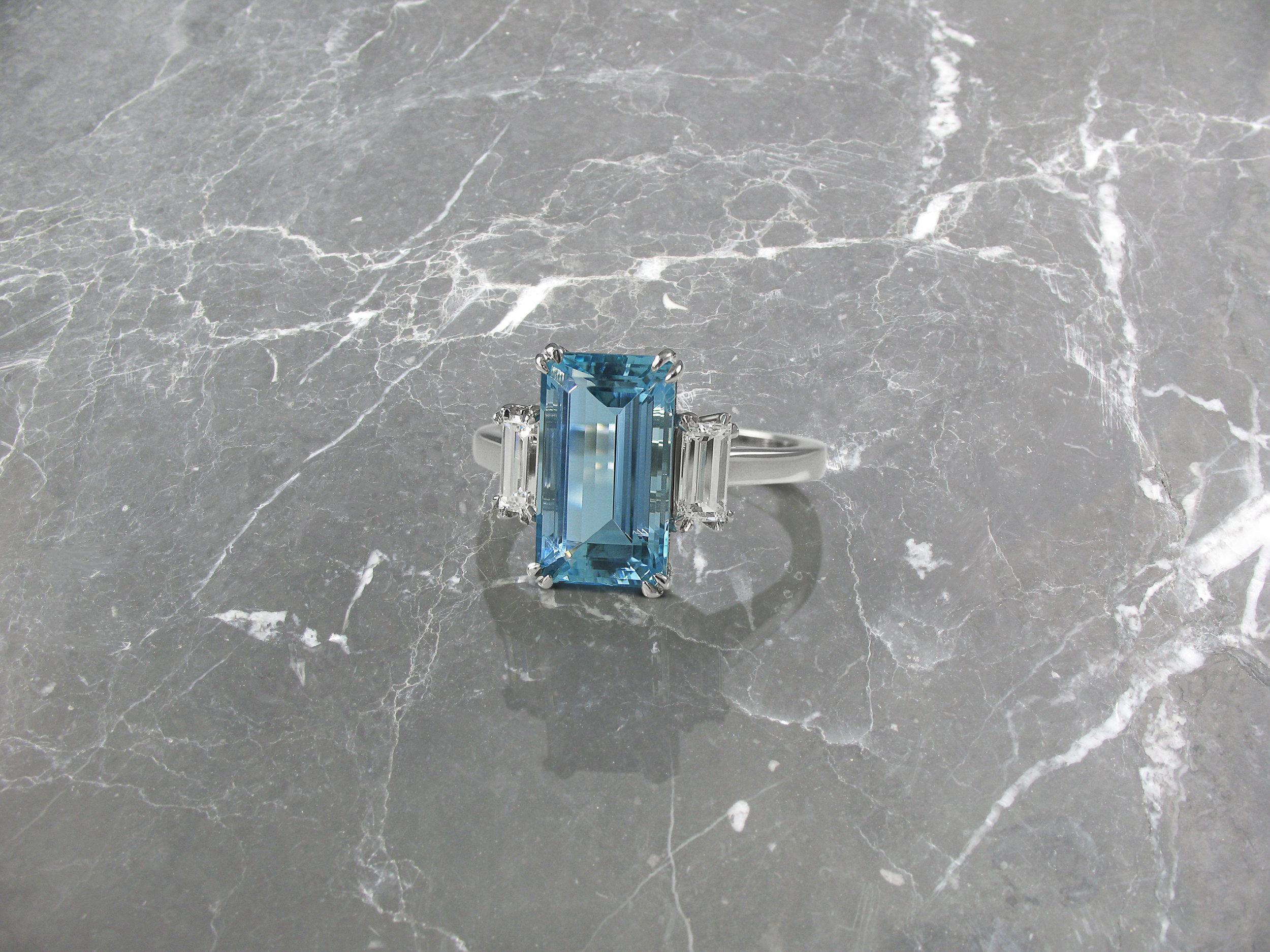 Emerald cut aquamarine and diamond trilogy engagement ring