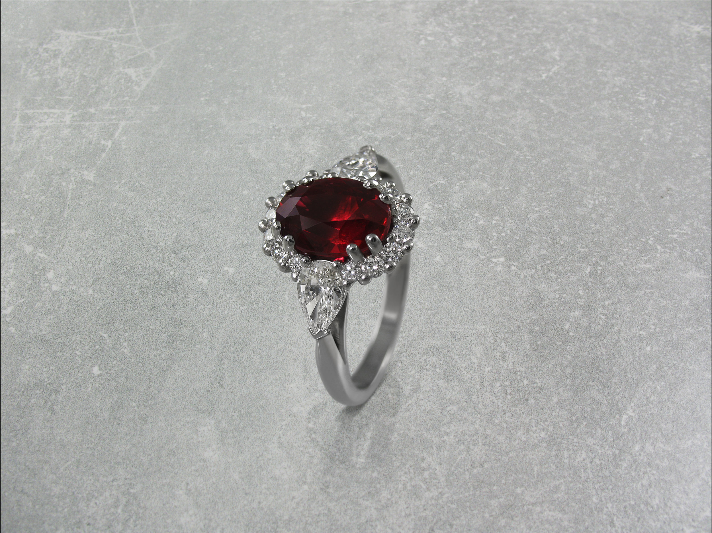 Oval ruby and diamond cluster engagement ring with pear shaped diamond shoulders