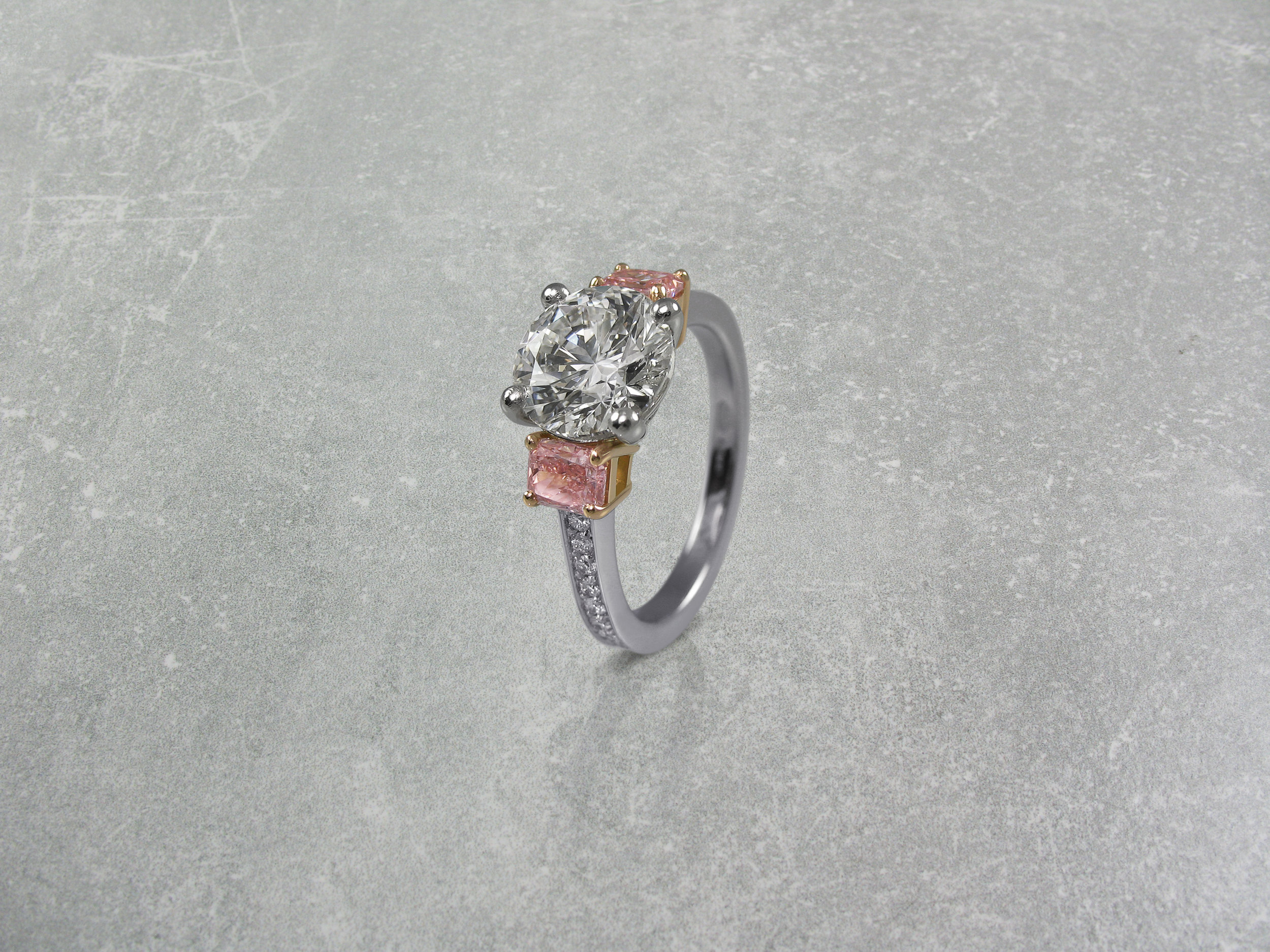 Round brilliant cut diamond and radiant cut pink diamond trilogy engagement ring