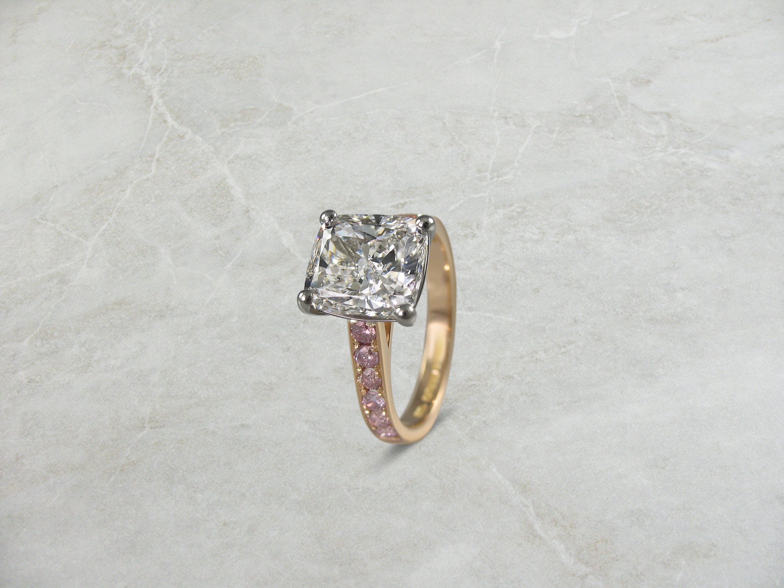 Diamond engagement ring with fancy pink diamond shoulders