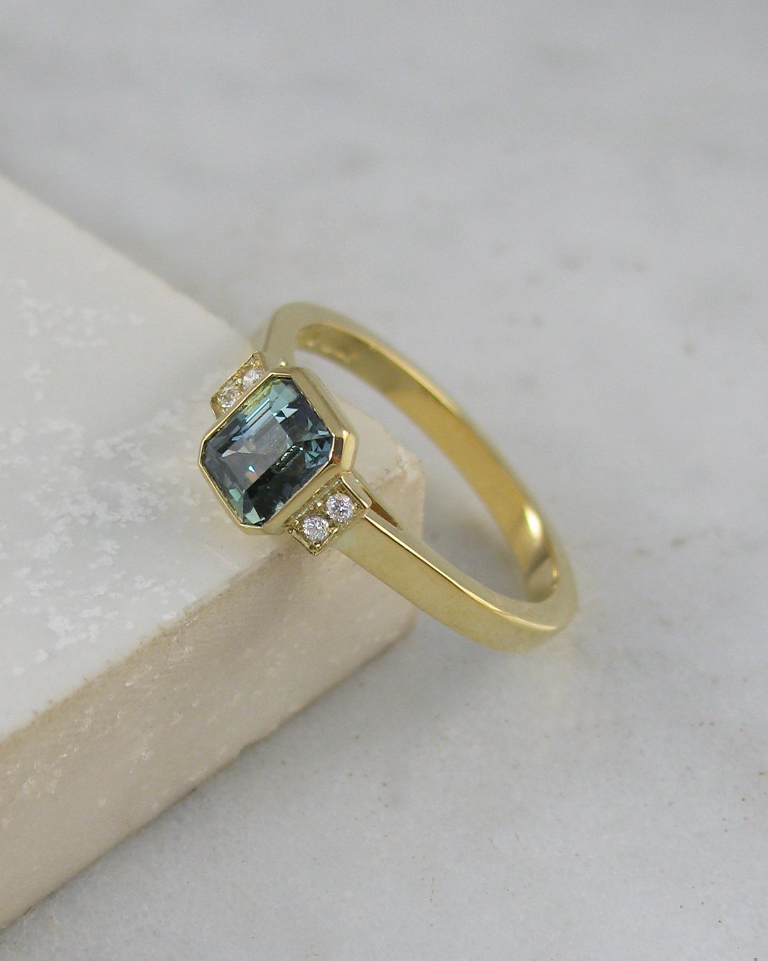 A stunning octagonal step cut natural teal blue sapphire engagement ring