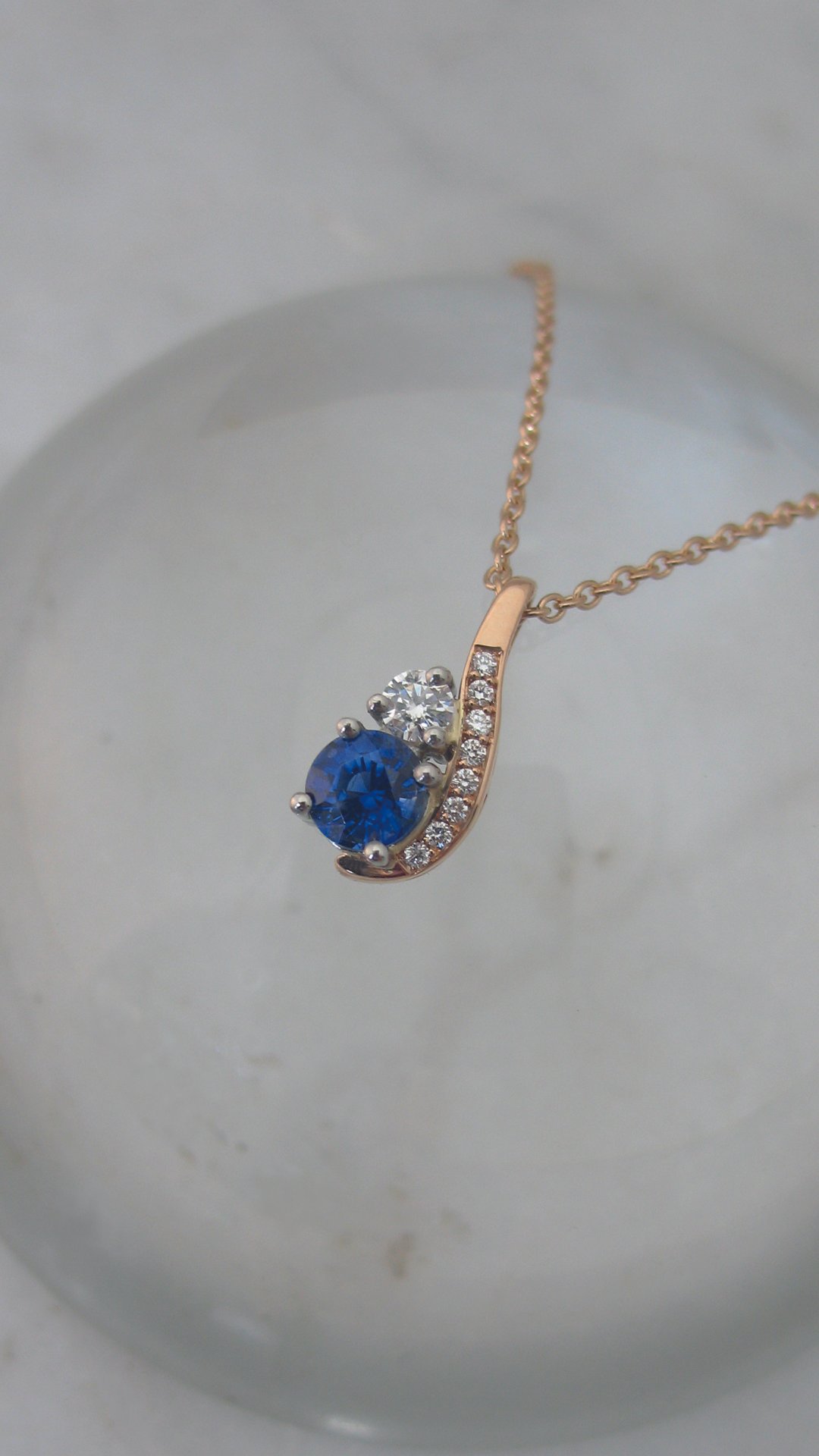 A gracefully curved diamond and sapphire&nbsp;pendant 
