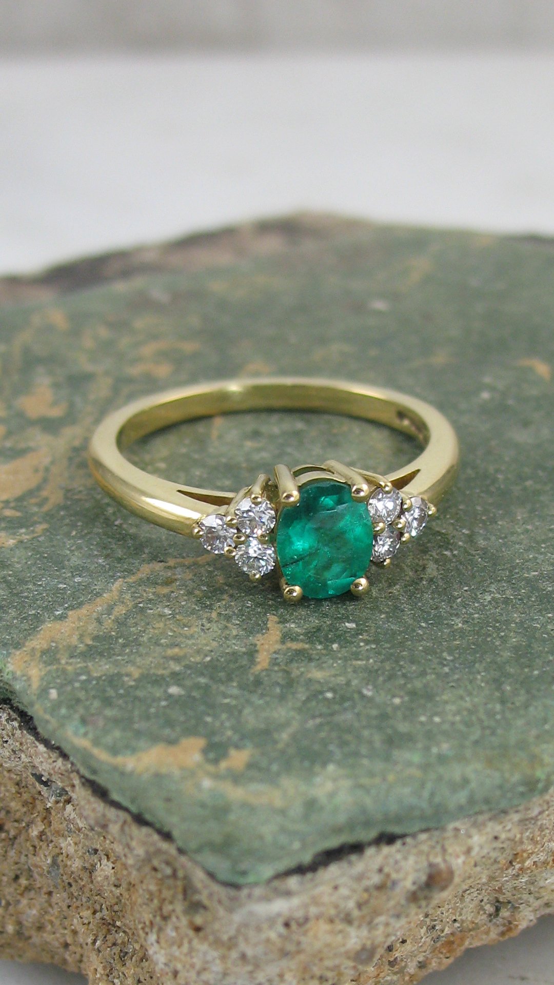 A bespoke emerald engagement ring with diamonds arranged in a trefoil design