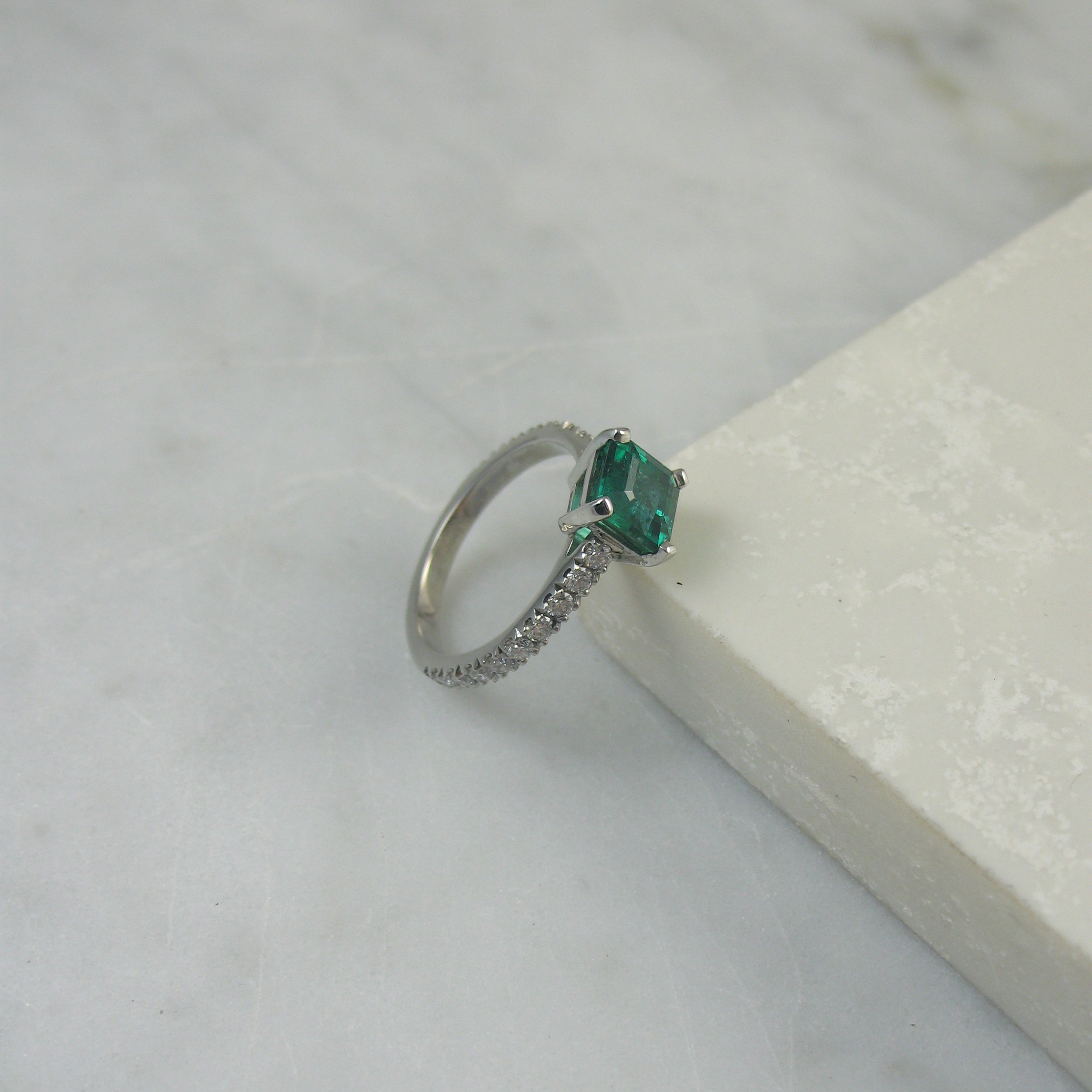 An emerald engagement ring with diamonds around the entire band