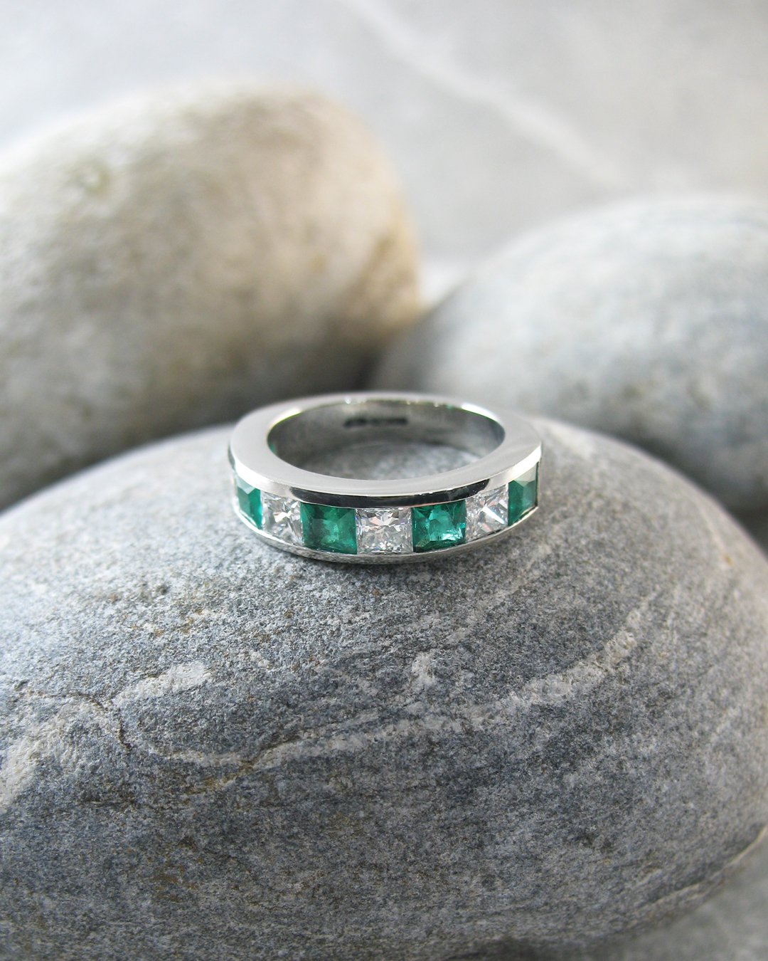 A custom emerald and diamond half eternity ring