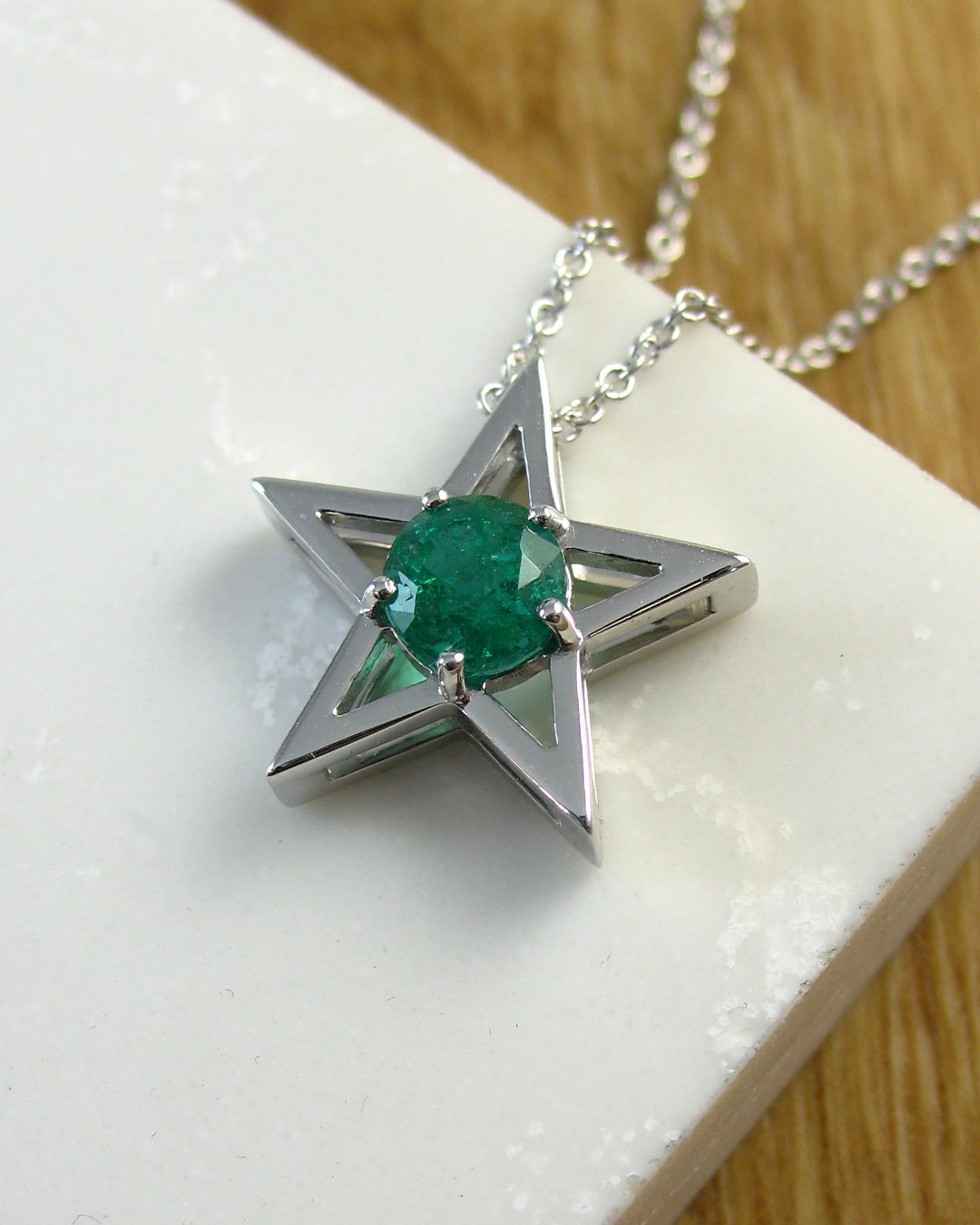 A white gold star shaped emerald pendant