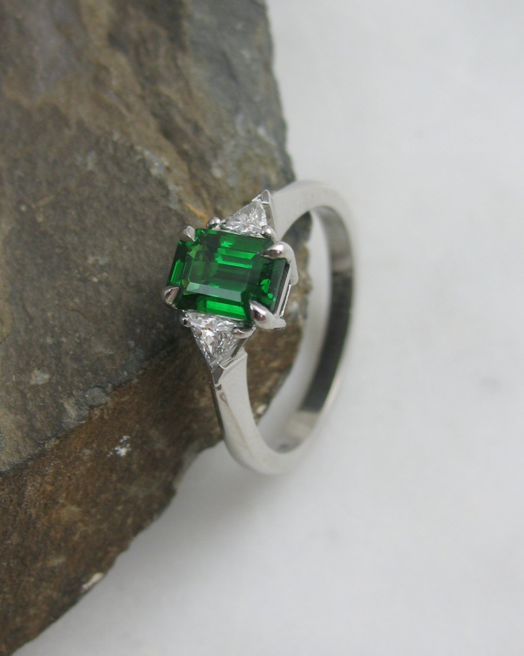 A diamond and vibrant green tsavorite engagement ring