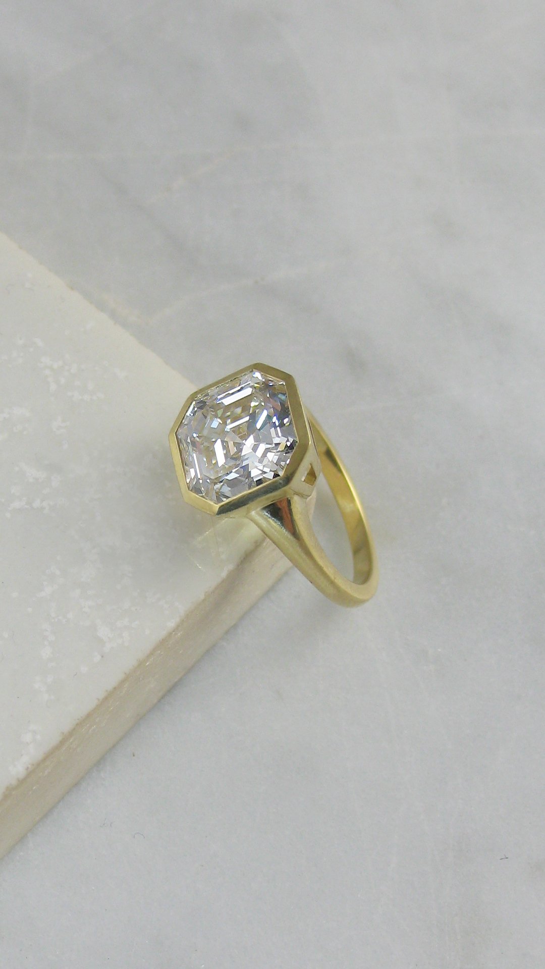 An Art Deco style bezel set Asscher cut diamond engagement ring