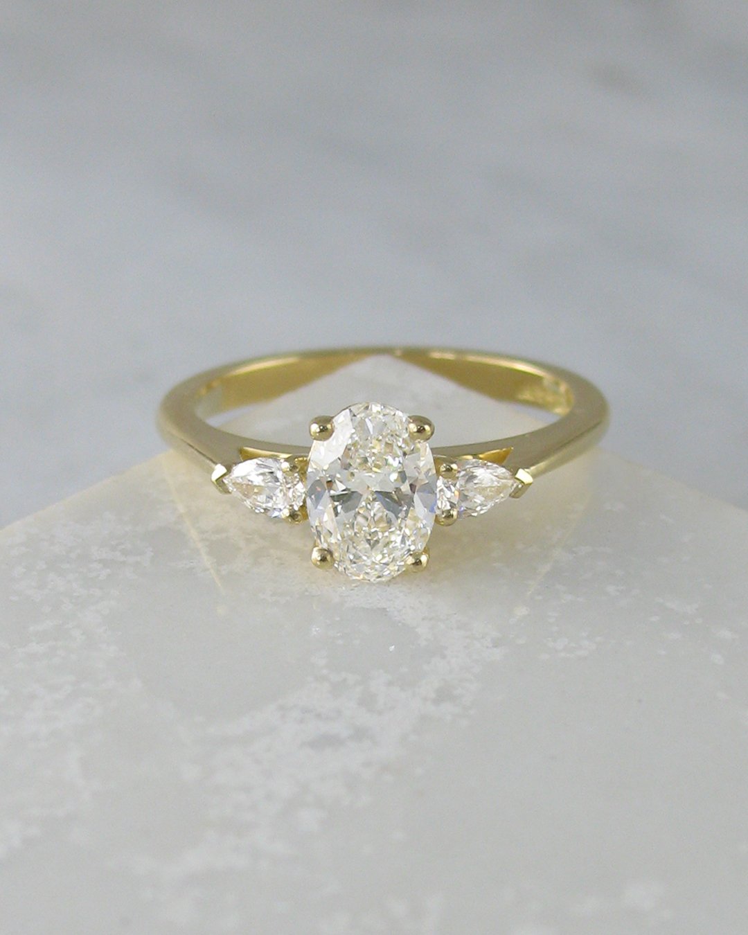 An elegant oval cut and pear shaped diamond engagement ring.