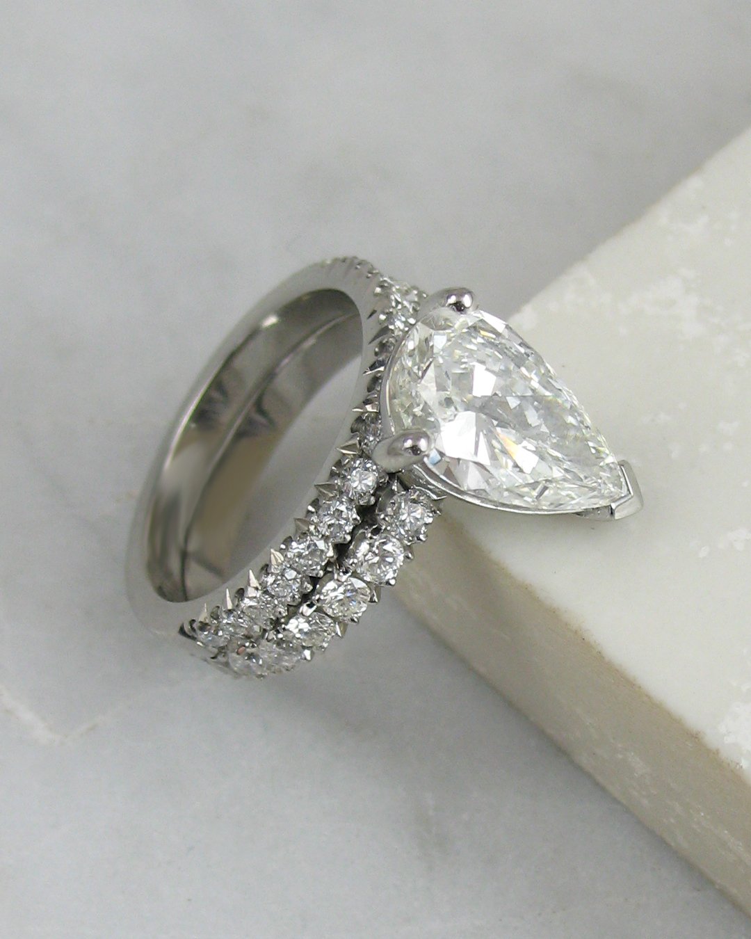 A matching wedding ring and pear shaped diamond engagement ring